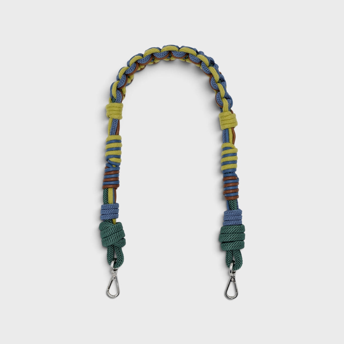 Multicolored braided macramé bag strap in bright and dark green, dark blue, and brown, shown on a light gray background.