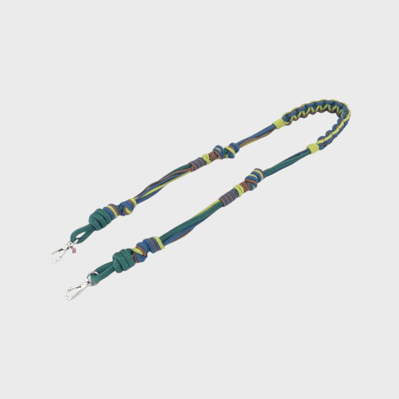 Multicolored braided macramé bag strap in bright and dark green, dark blue, and brown, shown on a light gray background.