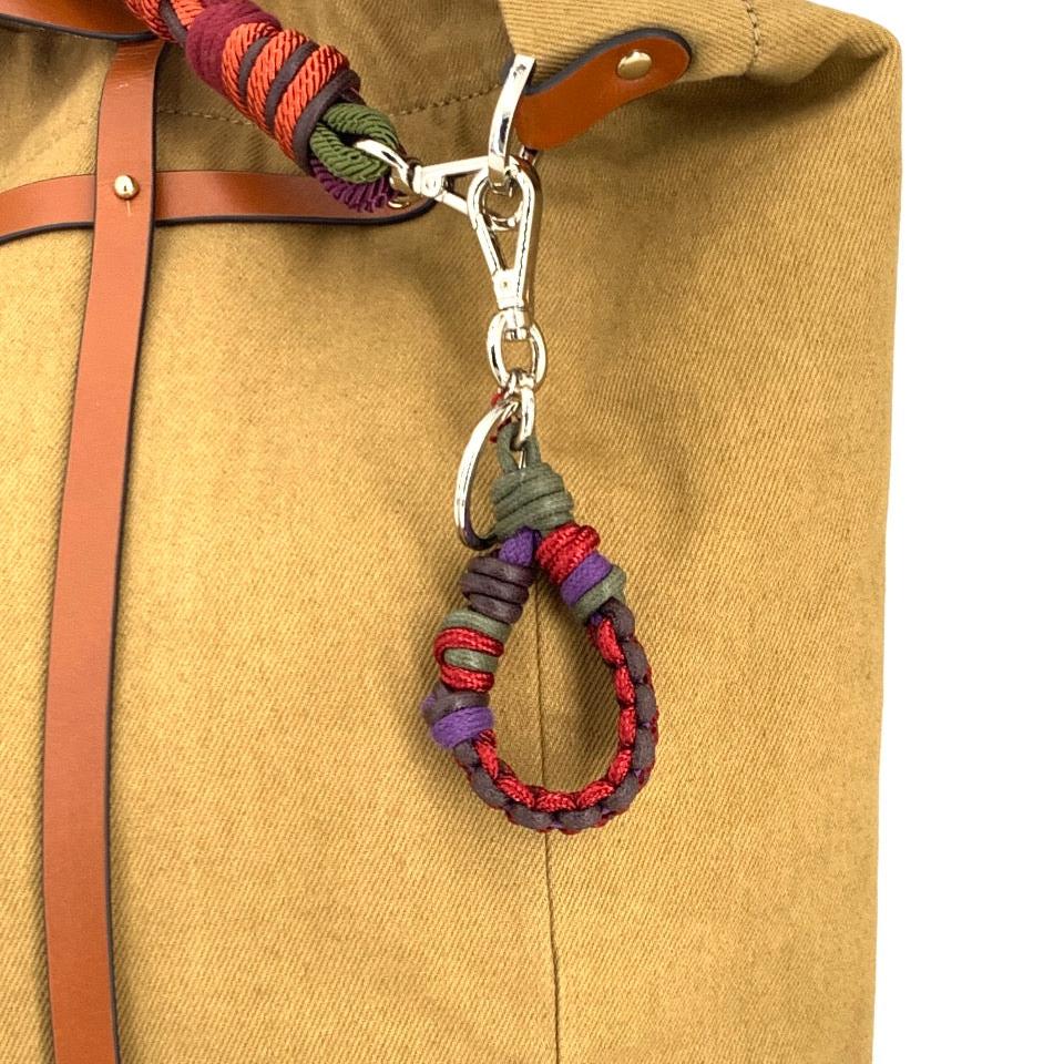 The brown, purple, pink and dark green Harold key ring on a mustard bag. 