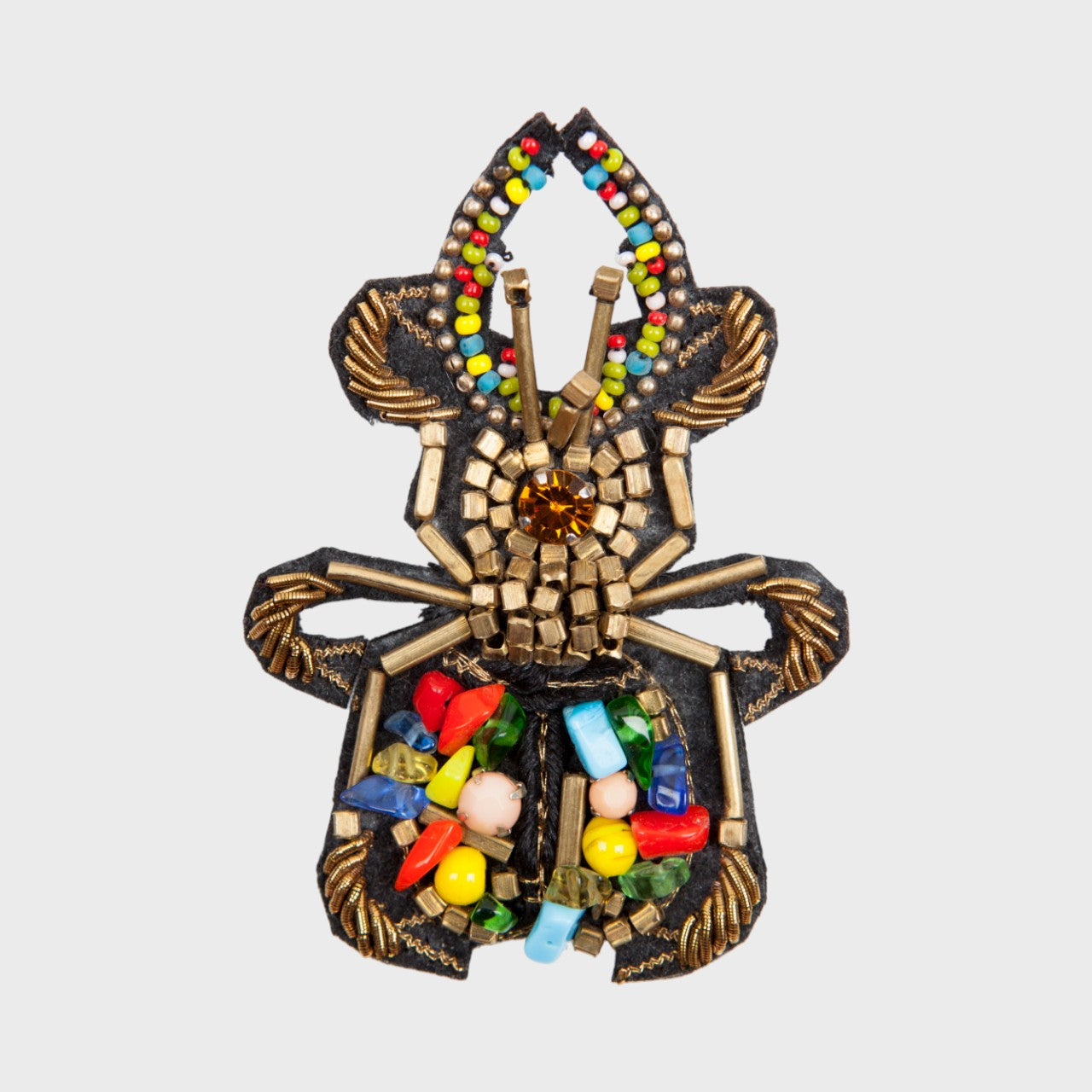 An embroidered brooch with yellow, gold and green, blue, red details. 
