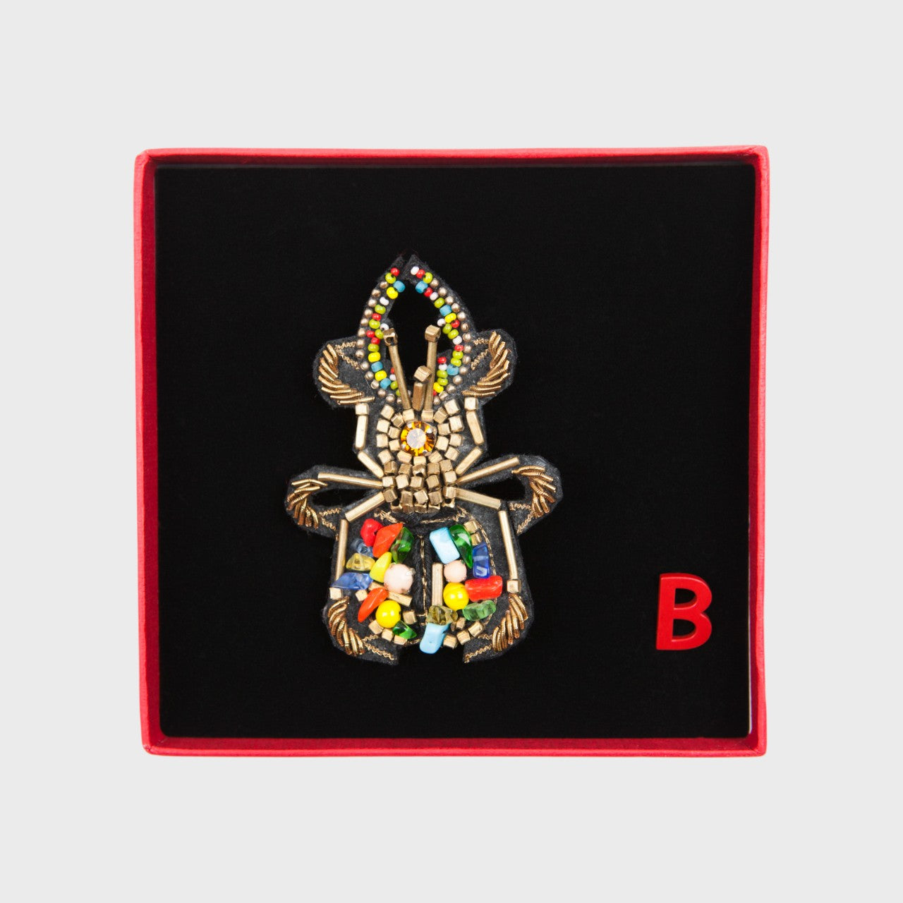An embroiered brooch representing a beetle in a box. 