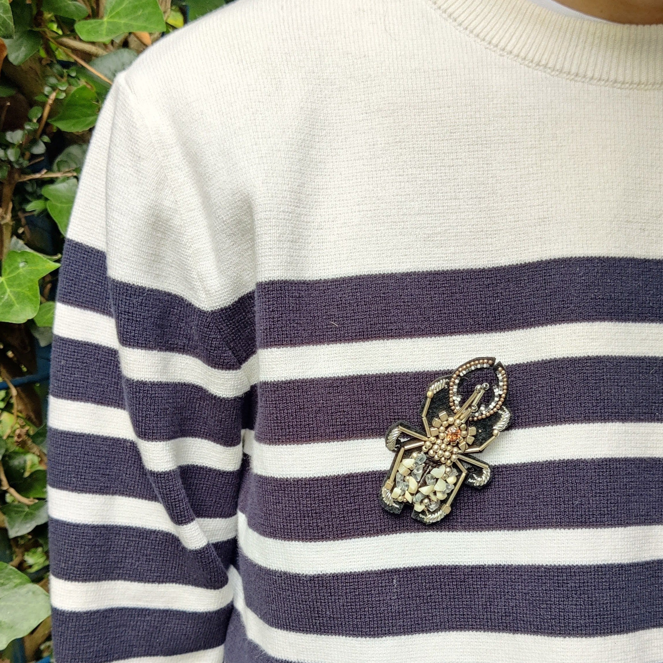 An embroidered beetle silver brooch worn by a model. 