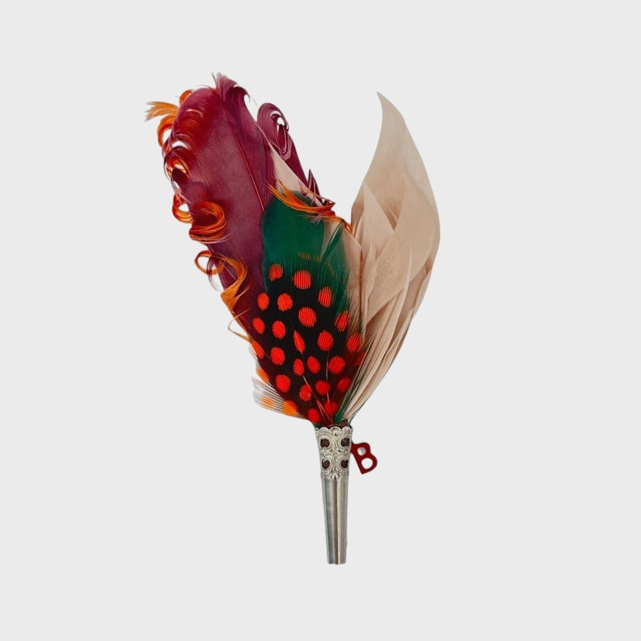 Orange, burgundy, green and beige feathered brooch on a light gray background