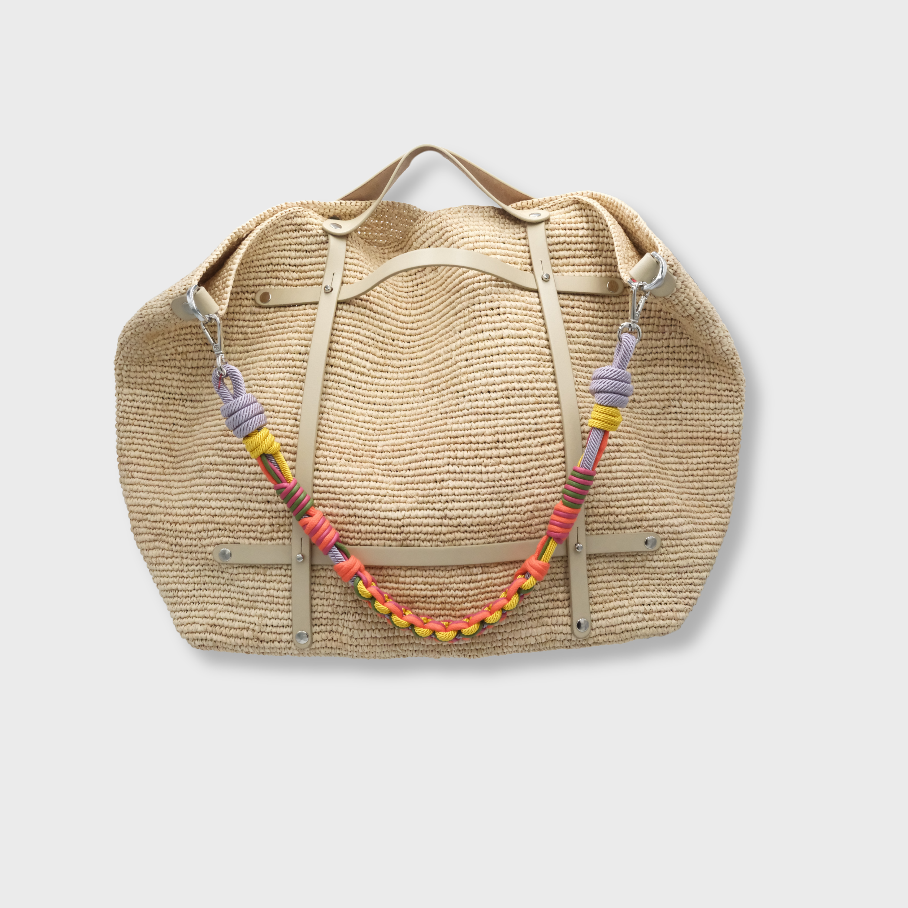 Beige raffia weekend or duffle bag with a white leather harness, paired with a colourful shoulder strap in pink, orange, yellow and purple.
