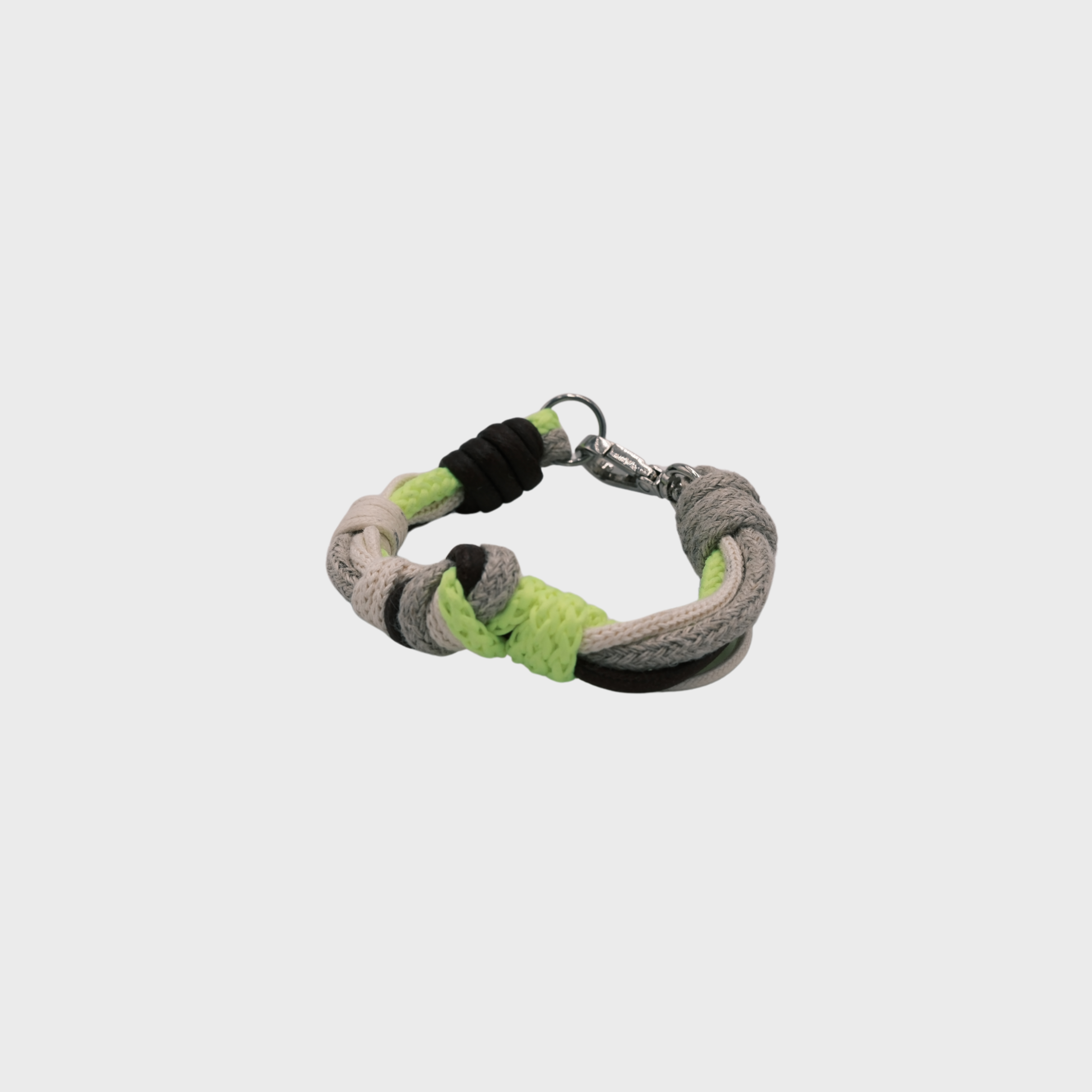A macramé bracelet with knotted details, featuring shades of neon yellow, beige and black, finished with a silver-tone metal clasp, set on a light gray background.