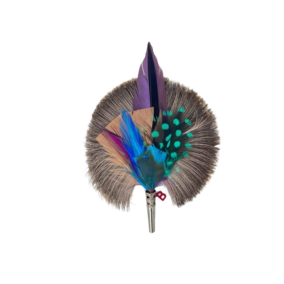 A feather brooch with purple, beige, green, blue and grey feathers and a silver metal clasp. 