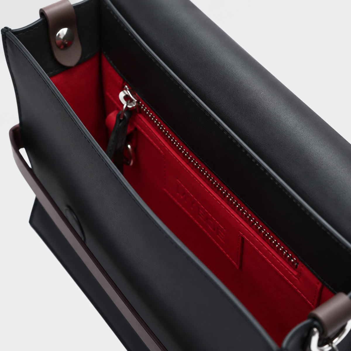 the interior of a genuine black leather bag with a red leather interior. 
