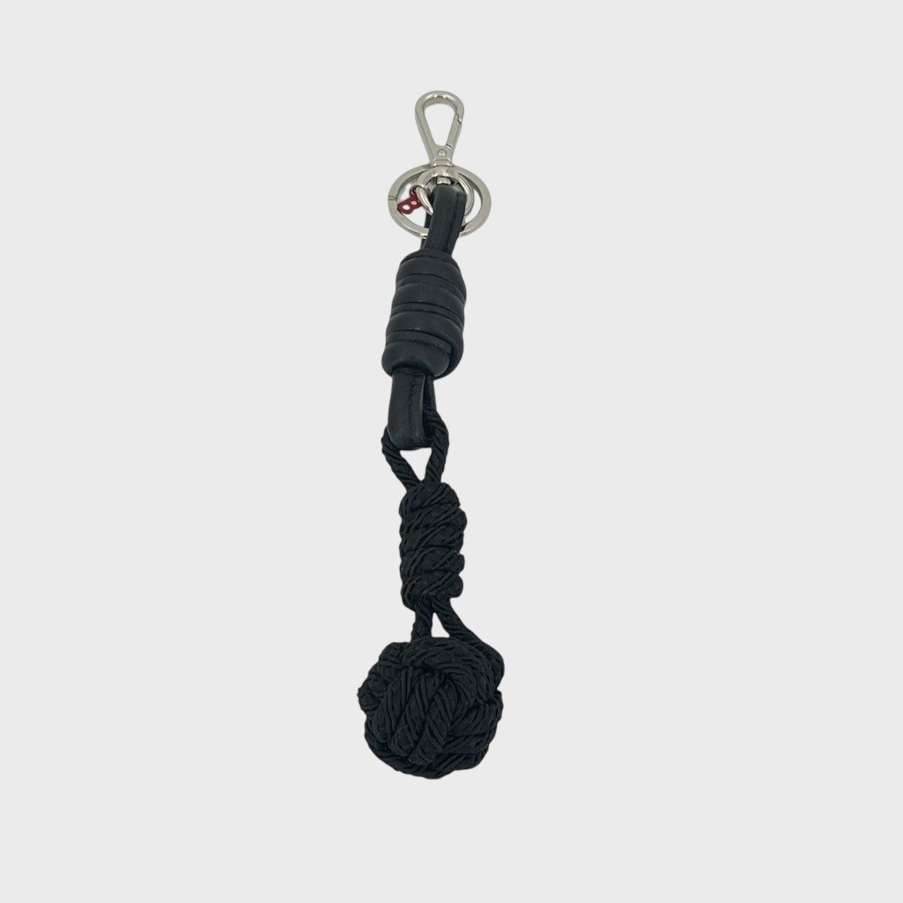 A macramé keychain representing a ball inspired by sailors knots. The straight upper part is leather black and the ball part is black. 