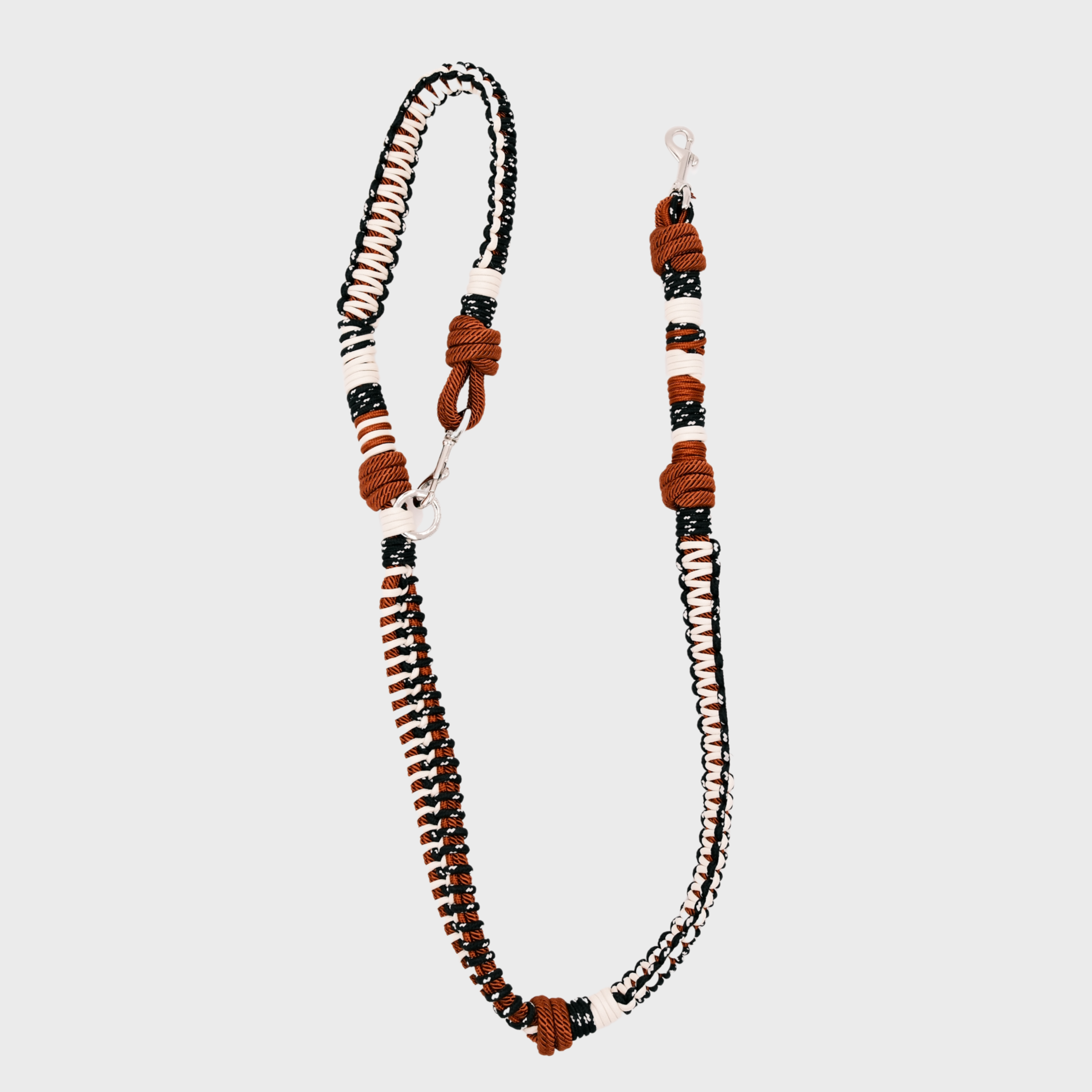 A braided macramé dog leash with brown, black, and white woven sections, and a silver metal hardware.