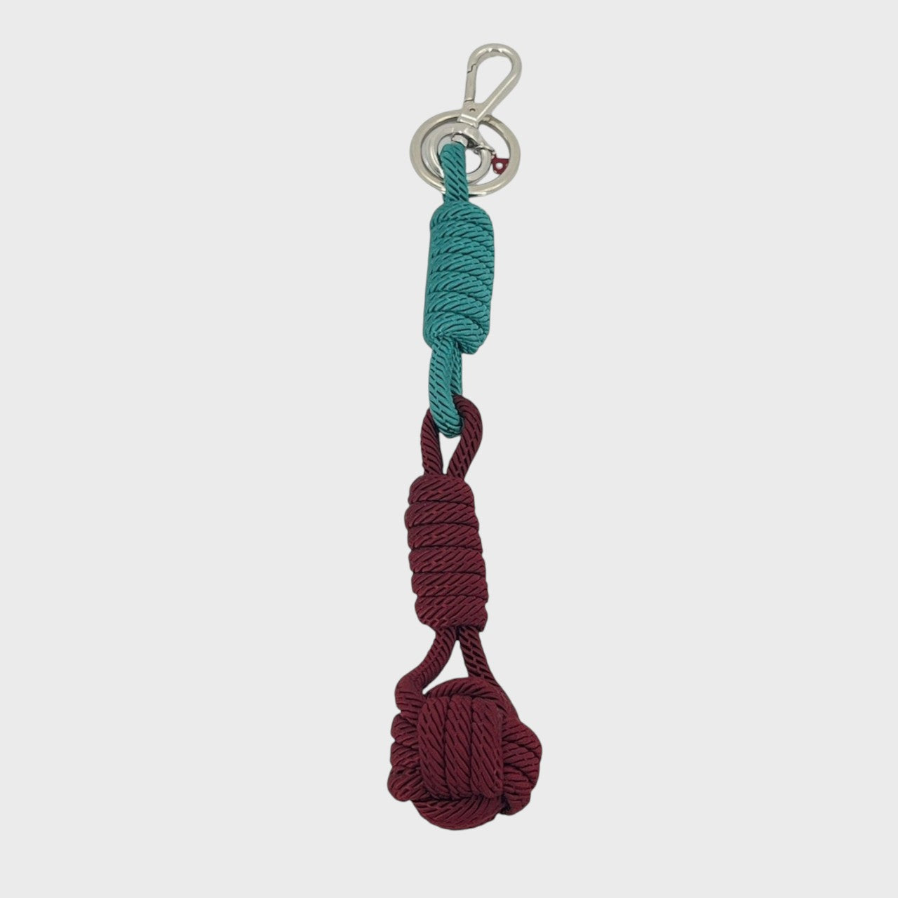 A macramé keychain representing a ball inspired by sailors knots. The straight upper part is blue and the ball part is burguny. 