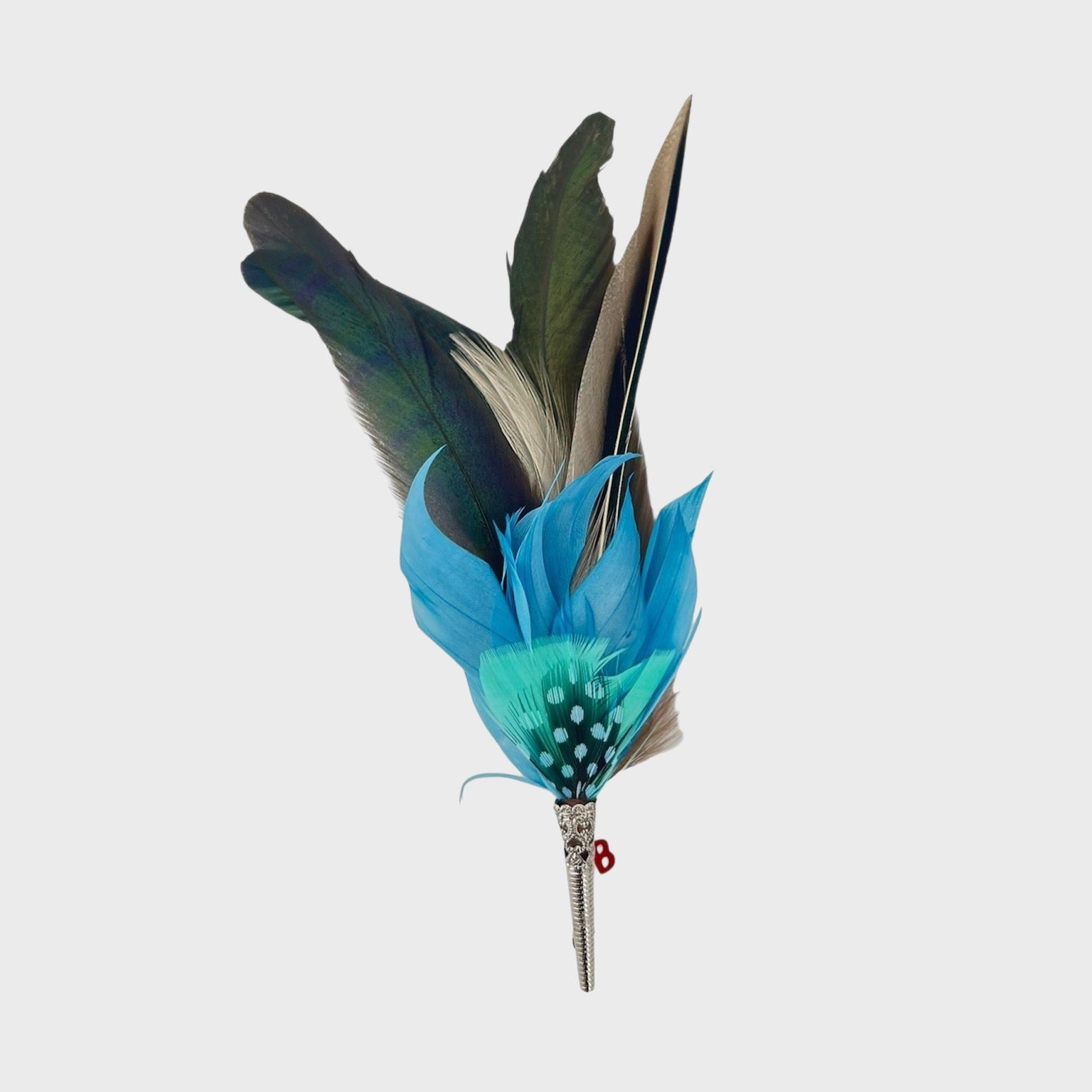 Large blue, green and grey feathered brooch on a light gray background