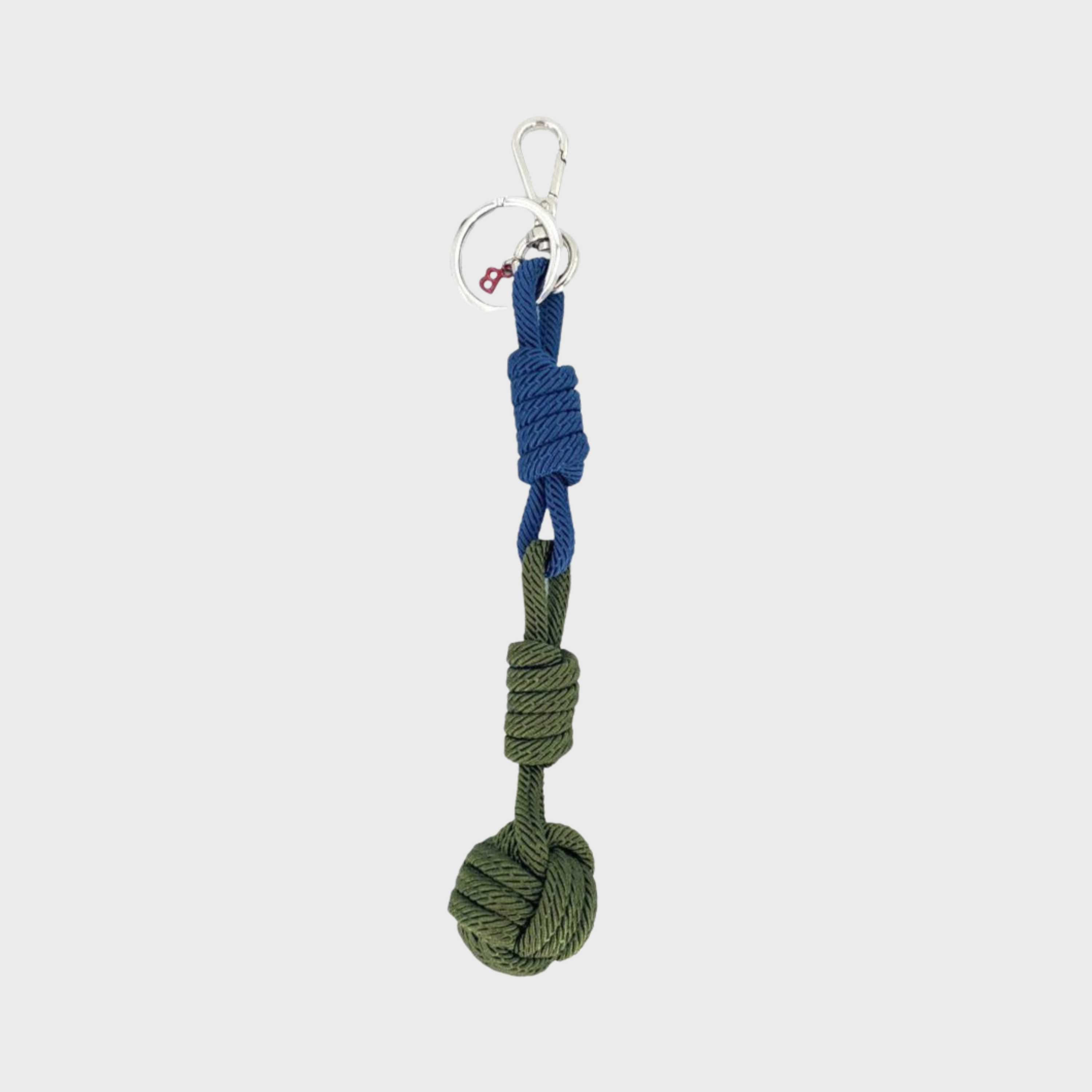 A macramé keychain representing a ball inspired by sailors knots. The straight upper part is blue and the ball part is green. 