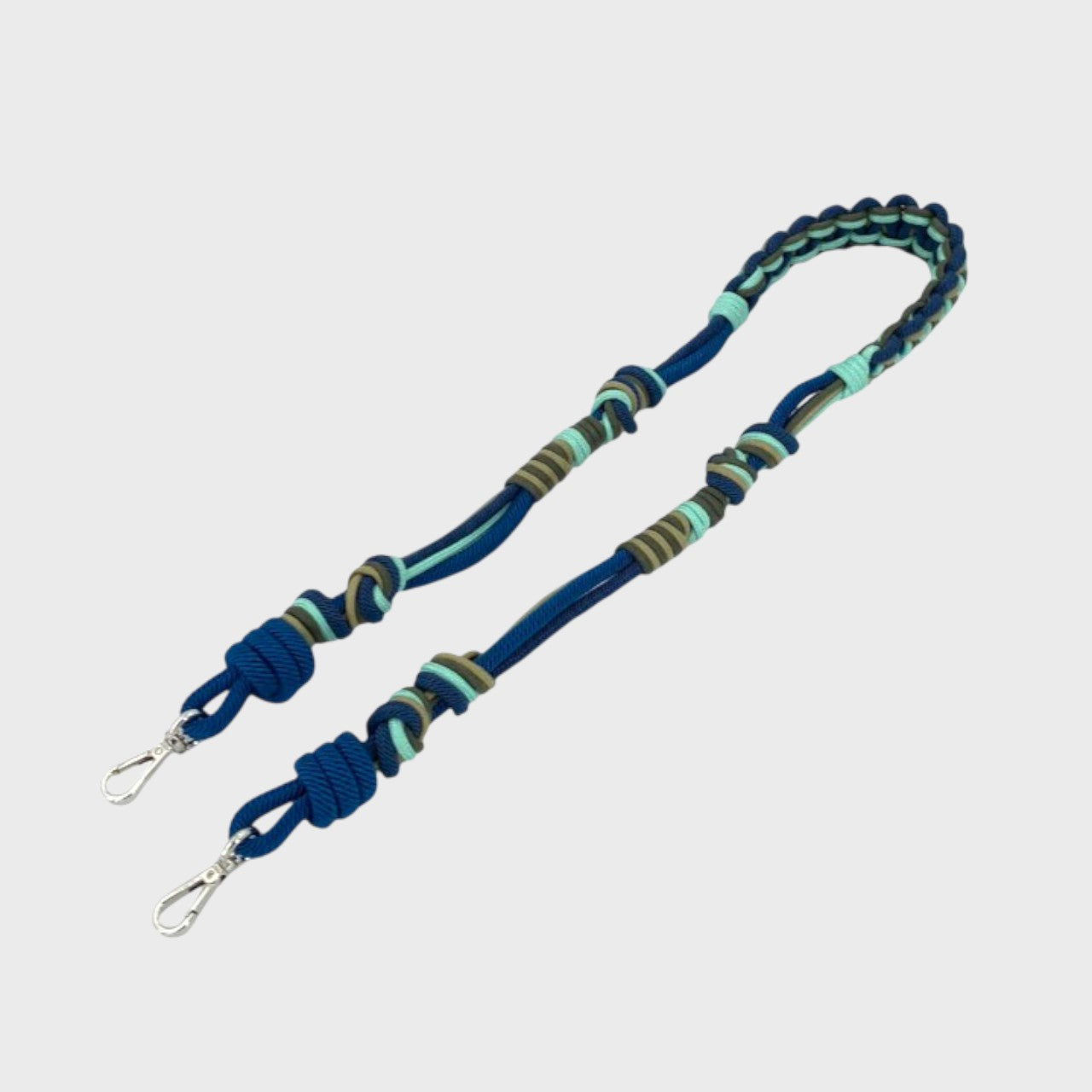 Multicolored braided macramé bag strap in bright blue, dark blue, and green with metal hooks on a light gray background.