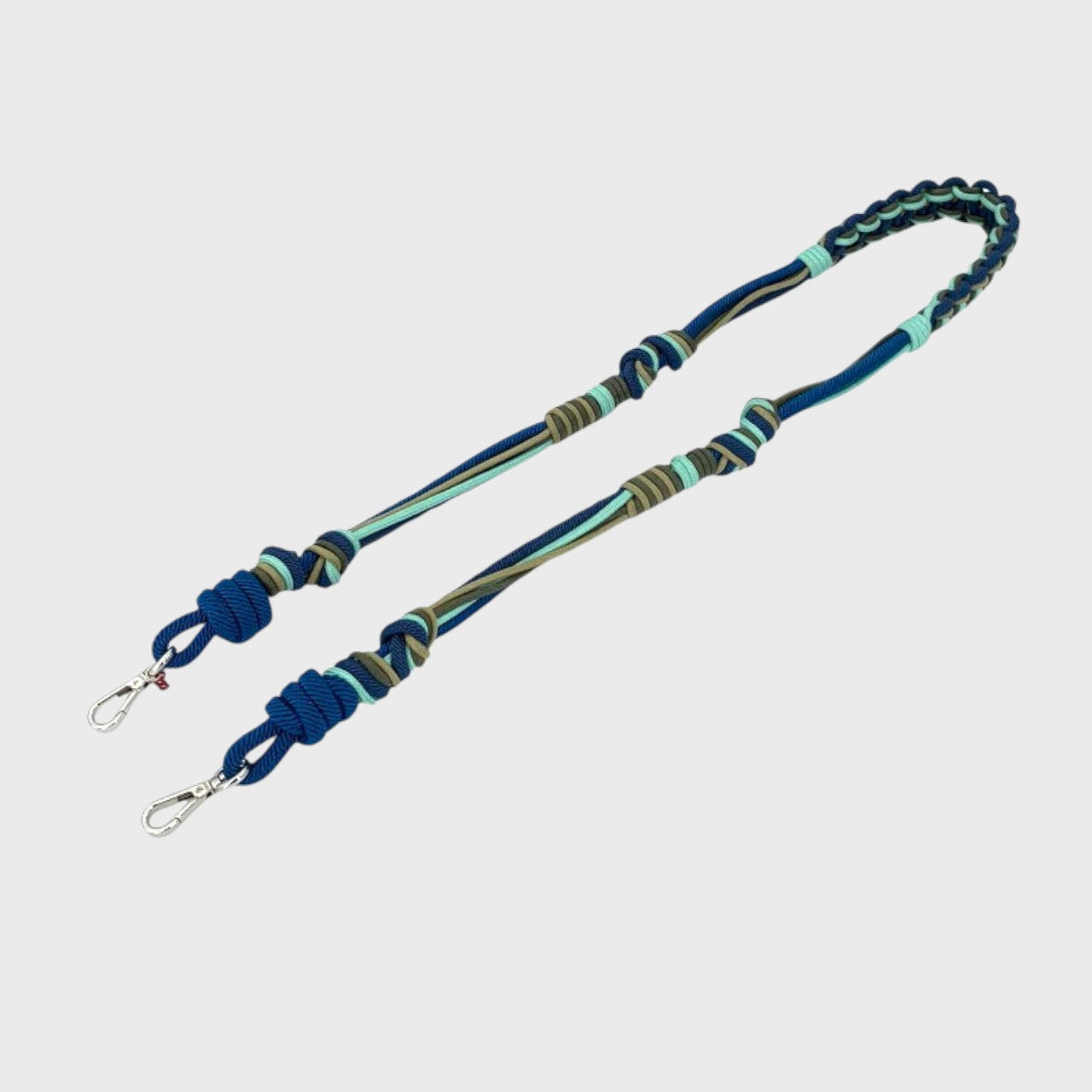 Multicolored braided macramé bag strap in bright blue, dark blue, and green with metal hooks on a light gray background.