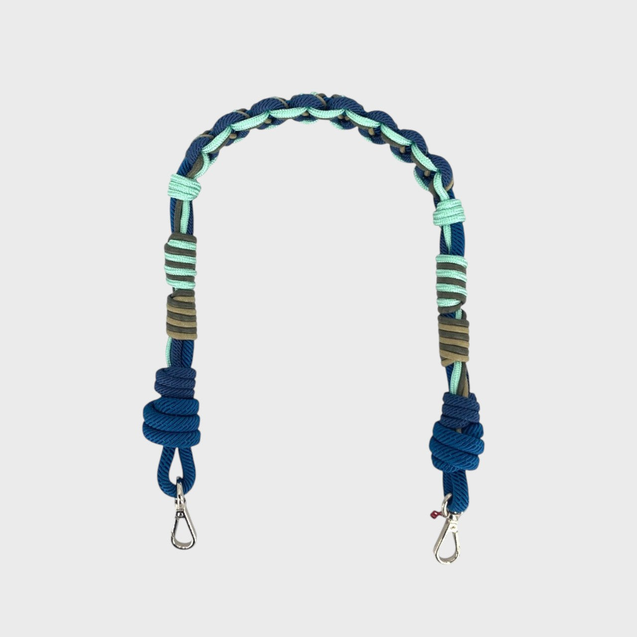Multicolored braided macramé bag strap in bright blue, dark blue, and green with metal hooks on a light gray background.