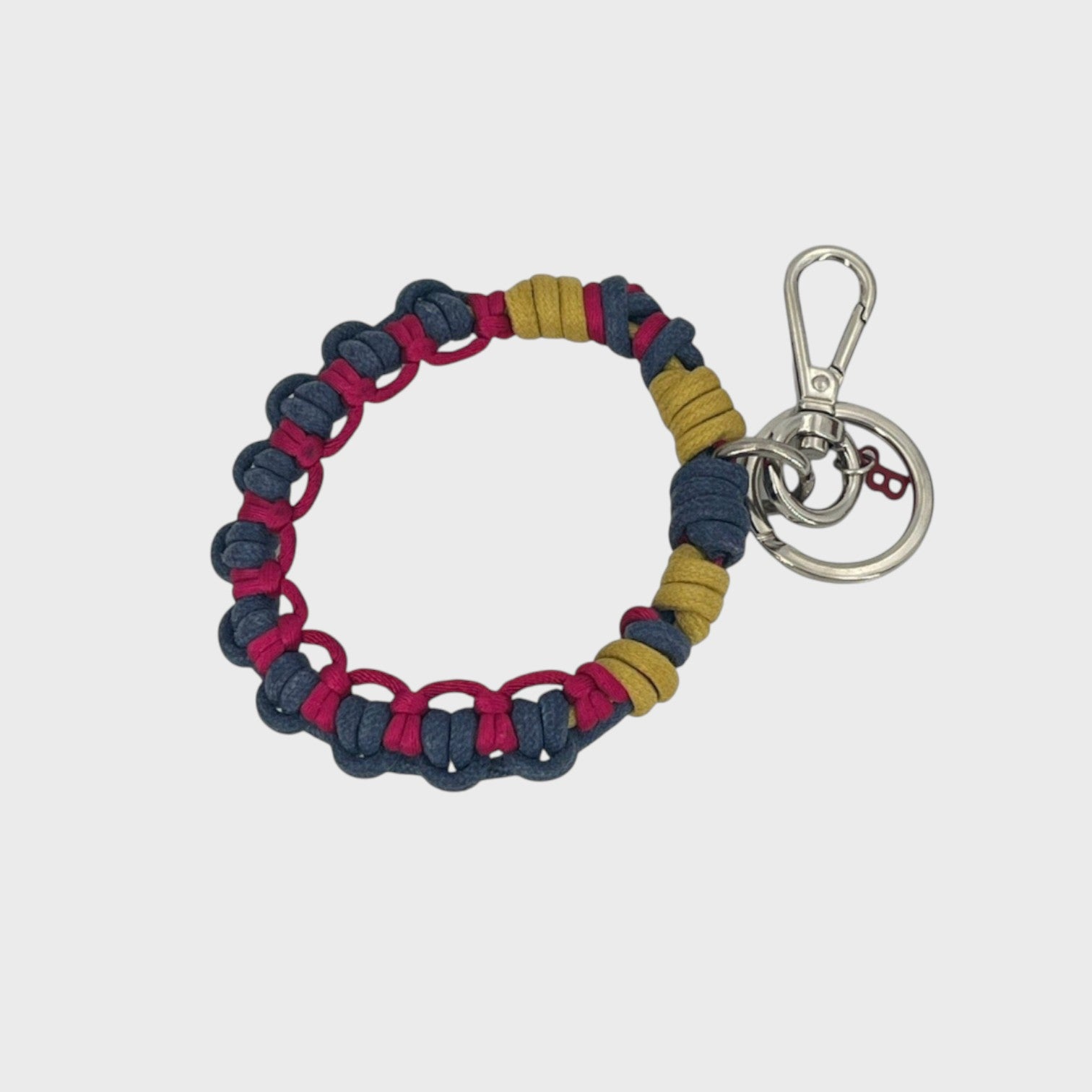 A woven macramé key chain with blue, yellow and Fuschia patterns, inspired by celtic knots, finished with silver-tone metal hardware.