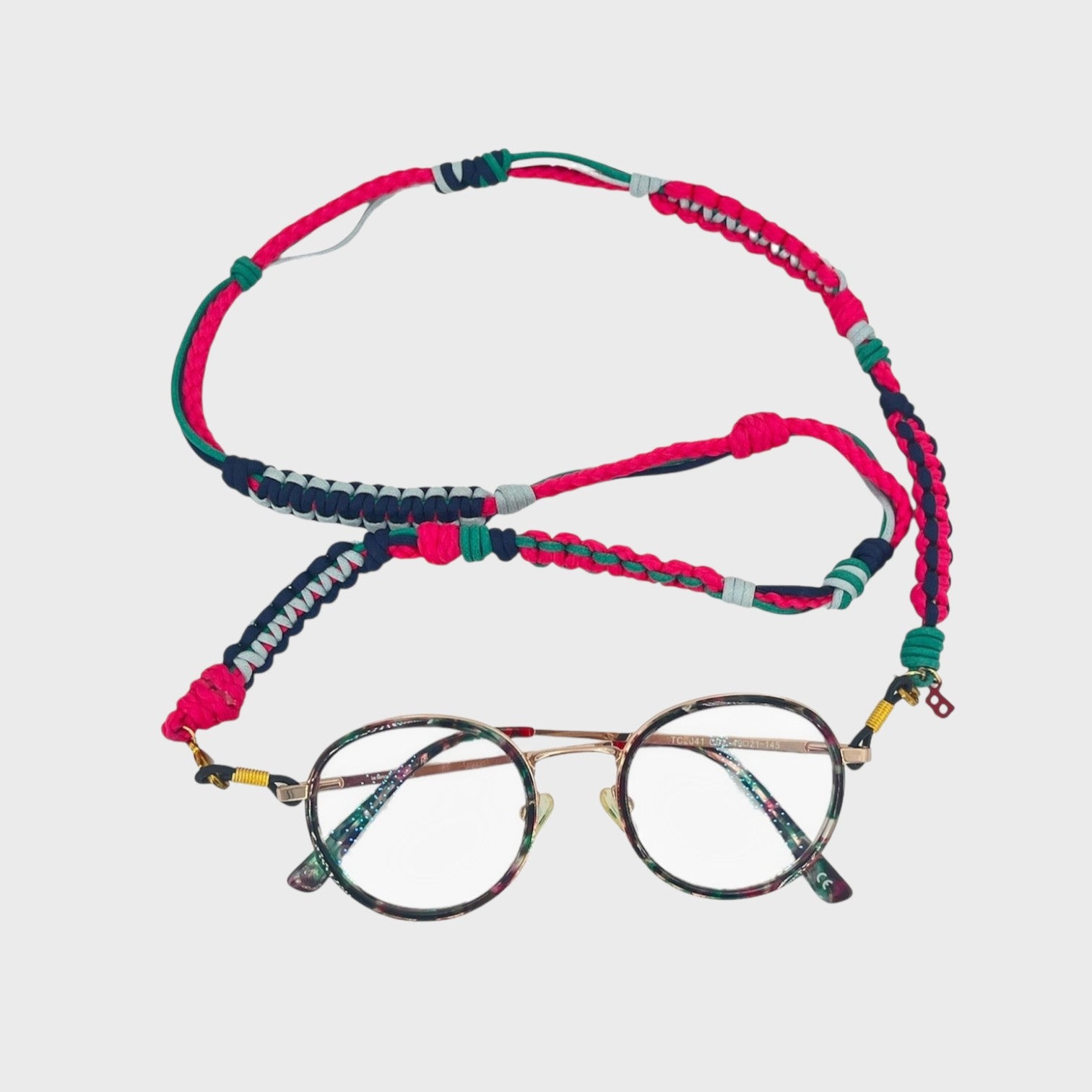 Woven eyeglass holder with bright pink, light and dark blue and green details on a white background