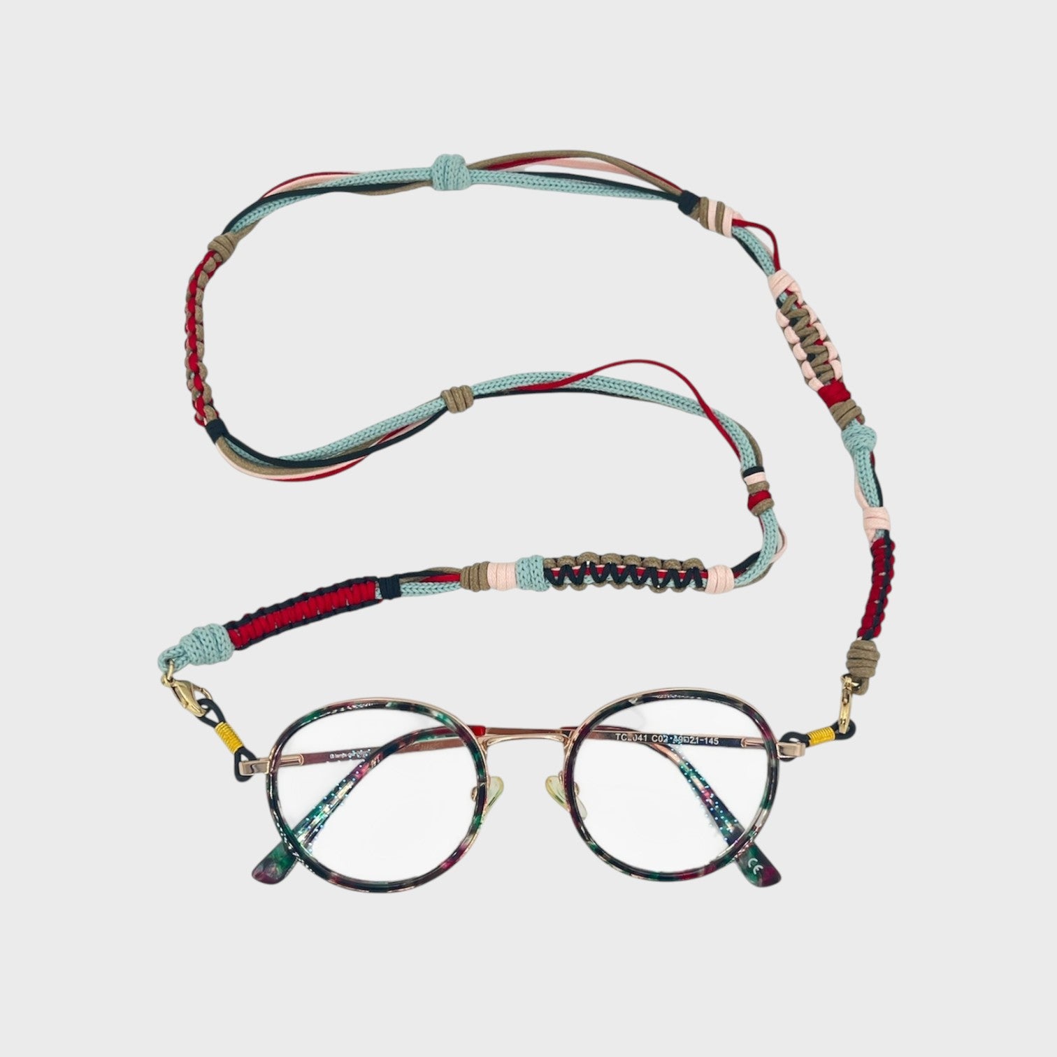 Woven eyeglass holder with light blue, red, light pink, brown and dark blue details on a white background