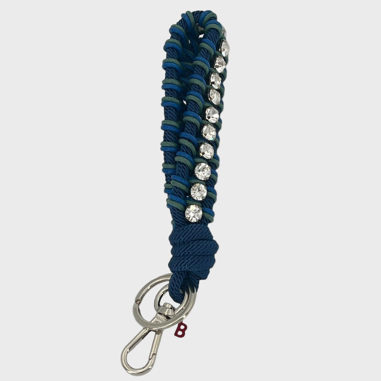 A macramé braided keychain strap featuring a dark blue and green pattern, accented with a vertical row of silver rhinestones, and finished with a silver metal lobster clasp on a light gray background.