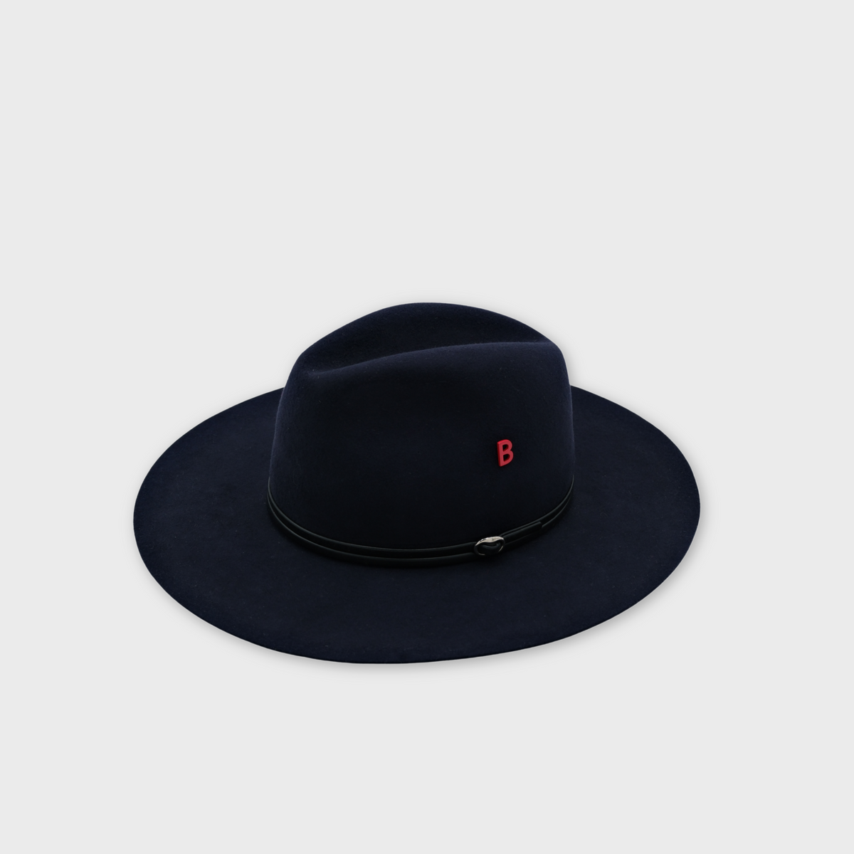 A dark blue felt wide-brim hat with a black leather band and a small red letter 'B' pin on the side, shown on a light gray background.