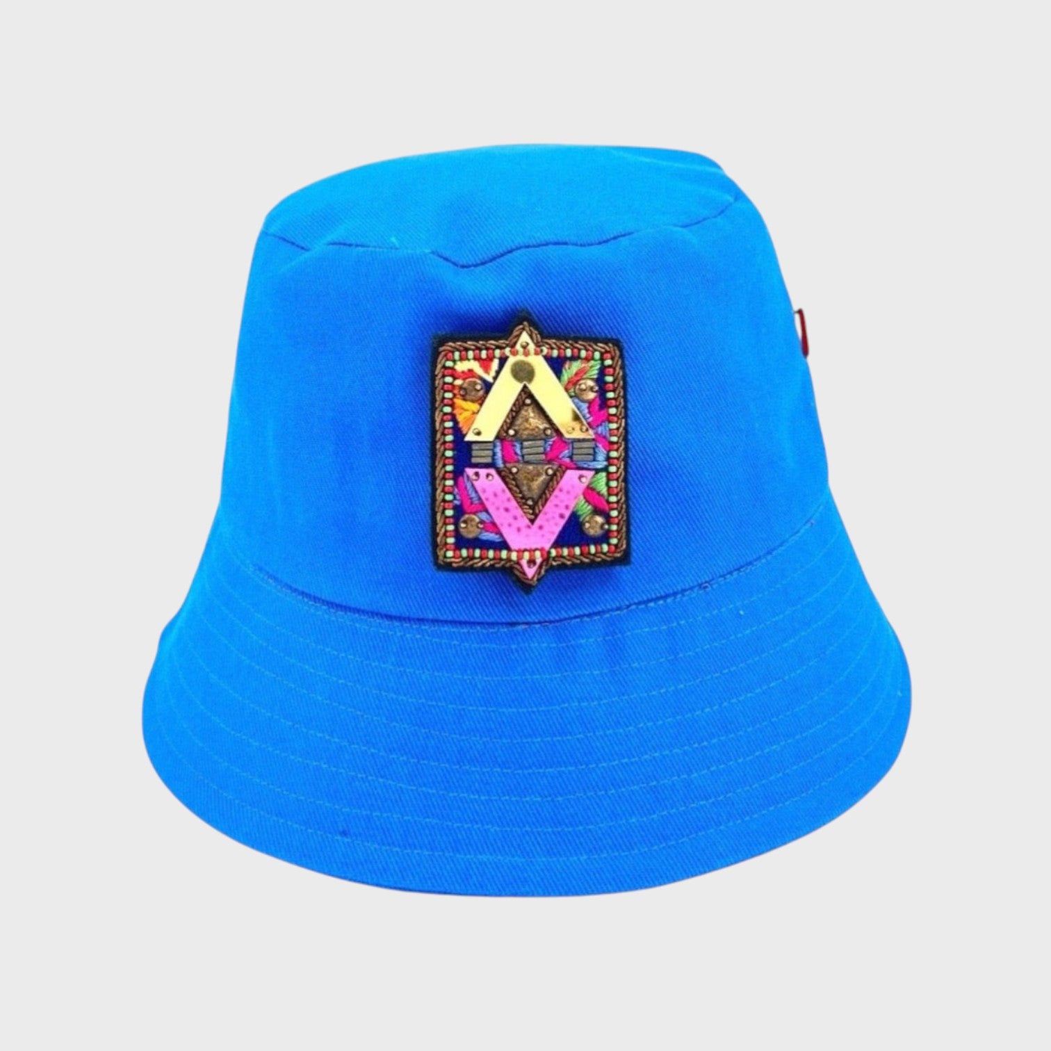 A blue cotton bucket hat with an element brooch pinned on it. 