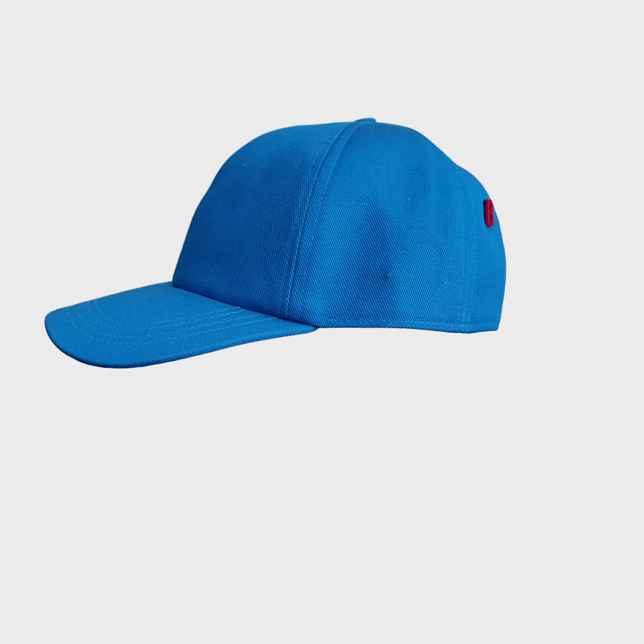 A cotton blue baseball cap on a light-grey background. 
