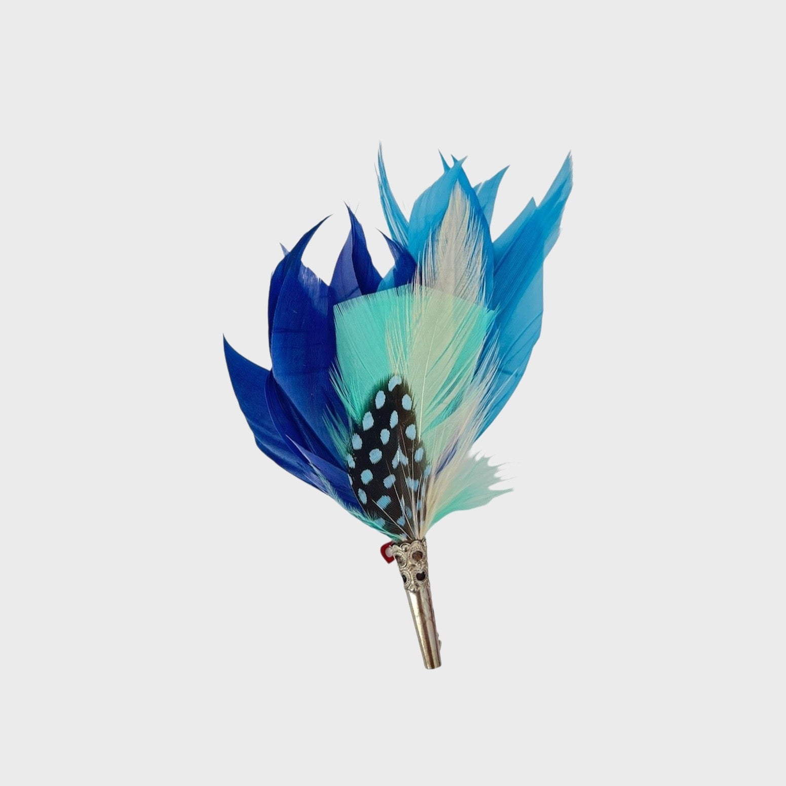 Different shades of blue on a feathered brooch on a light gray background