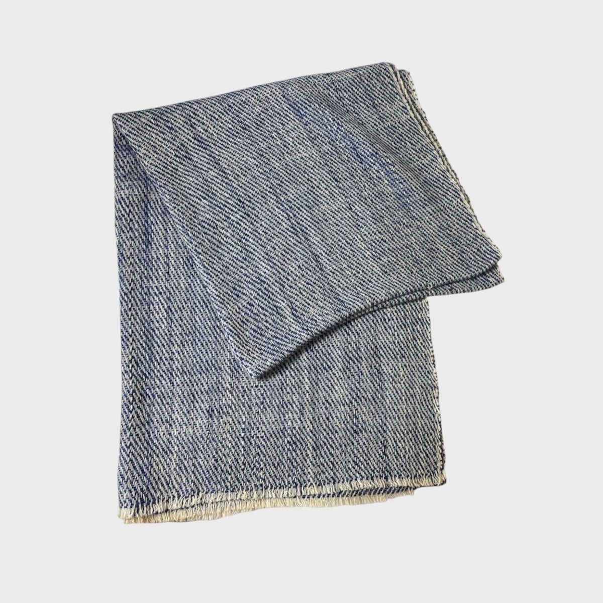 Folded blue cashmere shawl on a light gray background
