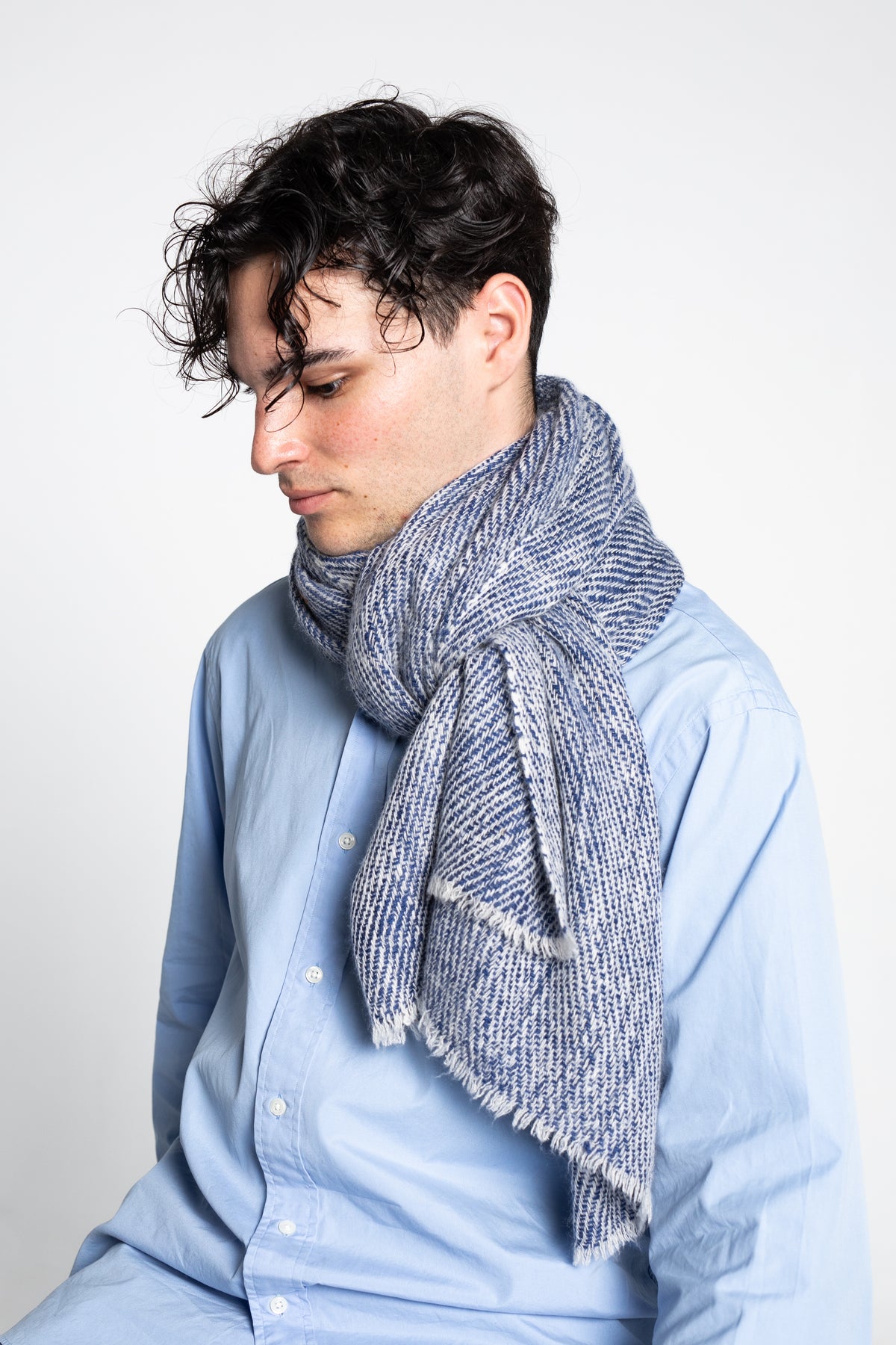 Person wearing a blue shirt and blue cashmere scarf against a white background