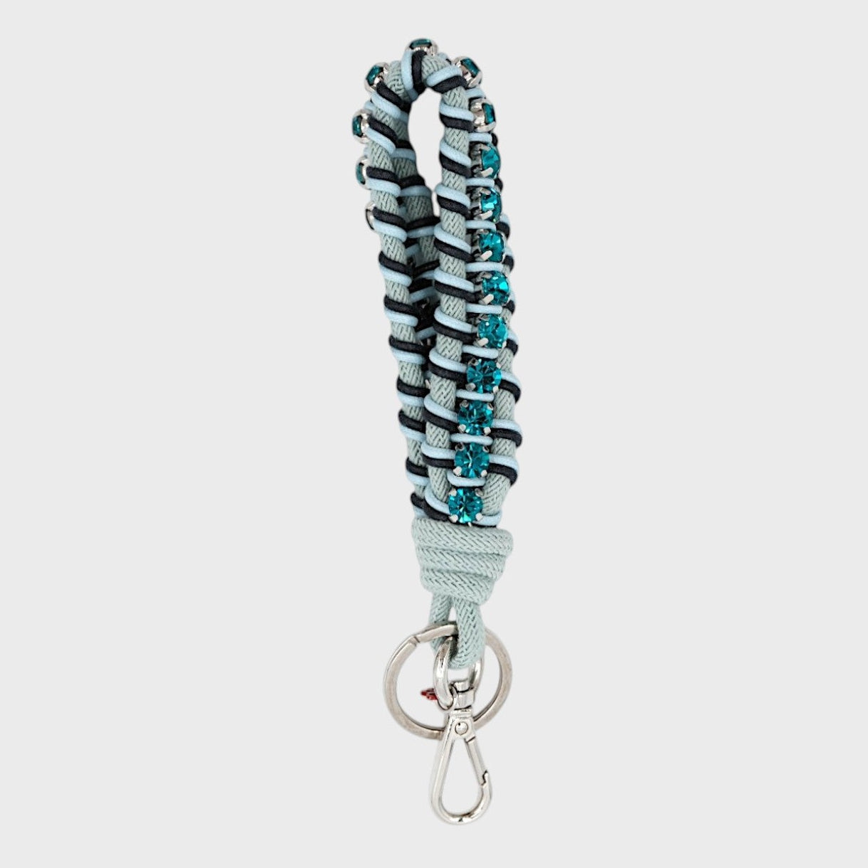 A macramé braided keychain strap featuring a dark and light blue pattern, accented with a vertical row of blue rhinestones, and finished with a silver metal lobster clasp on a light gray background.