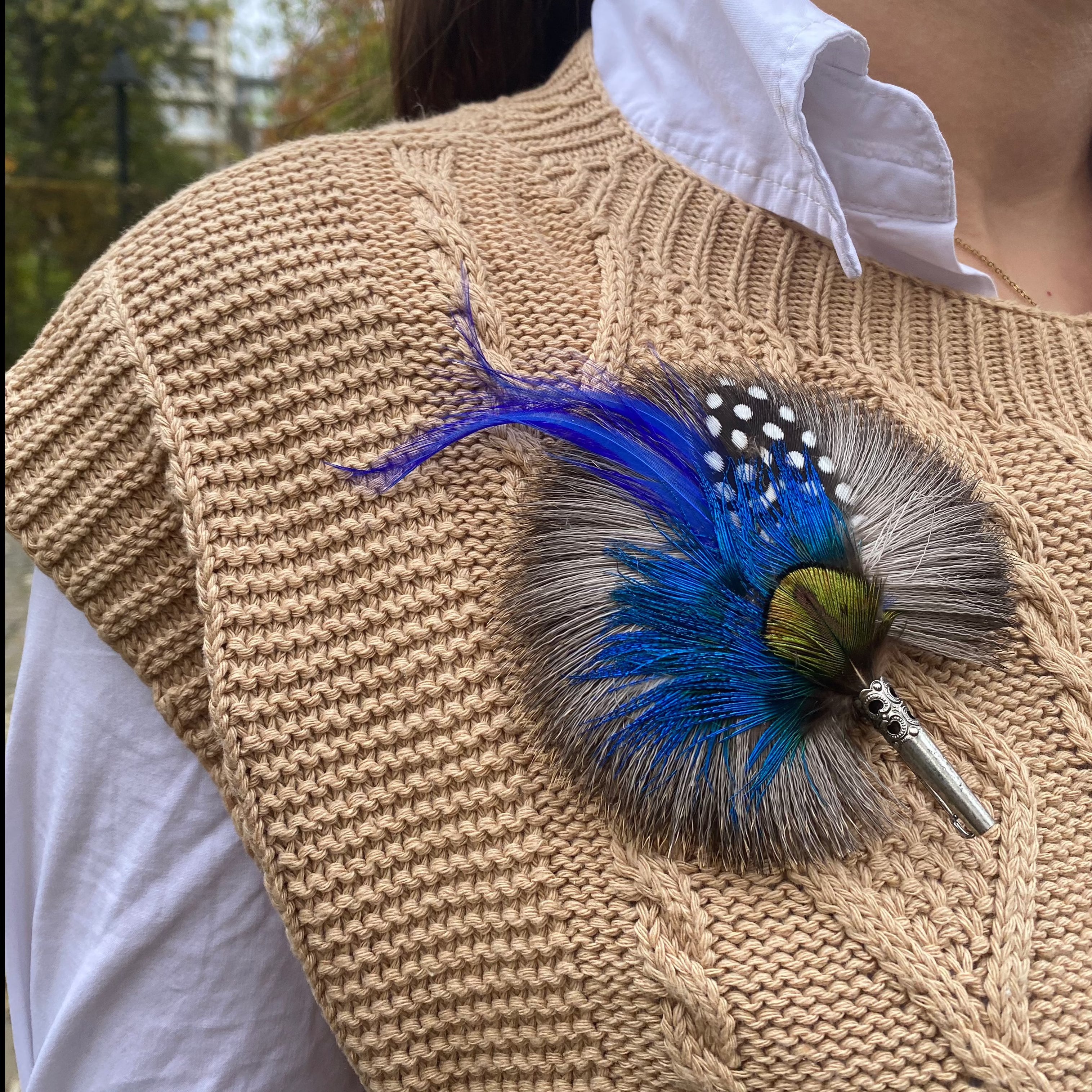 A model wearing the round blue feather brooch. 