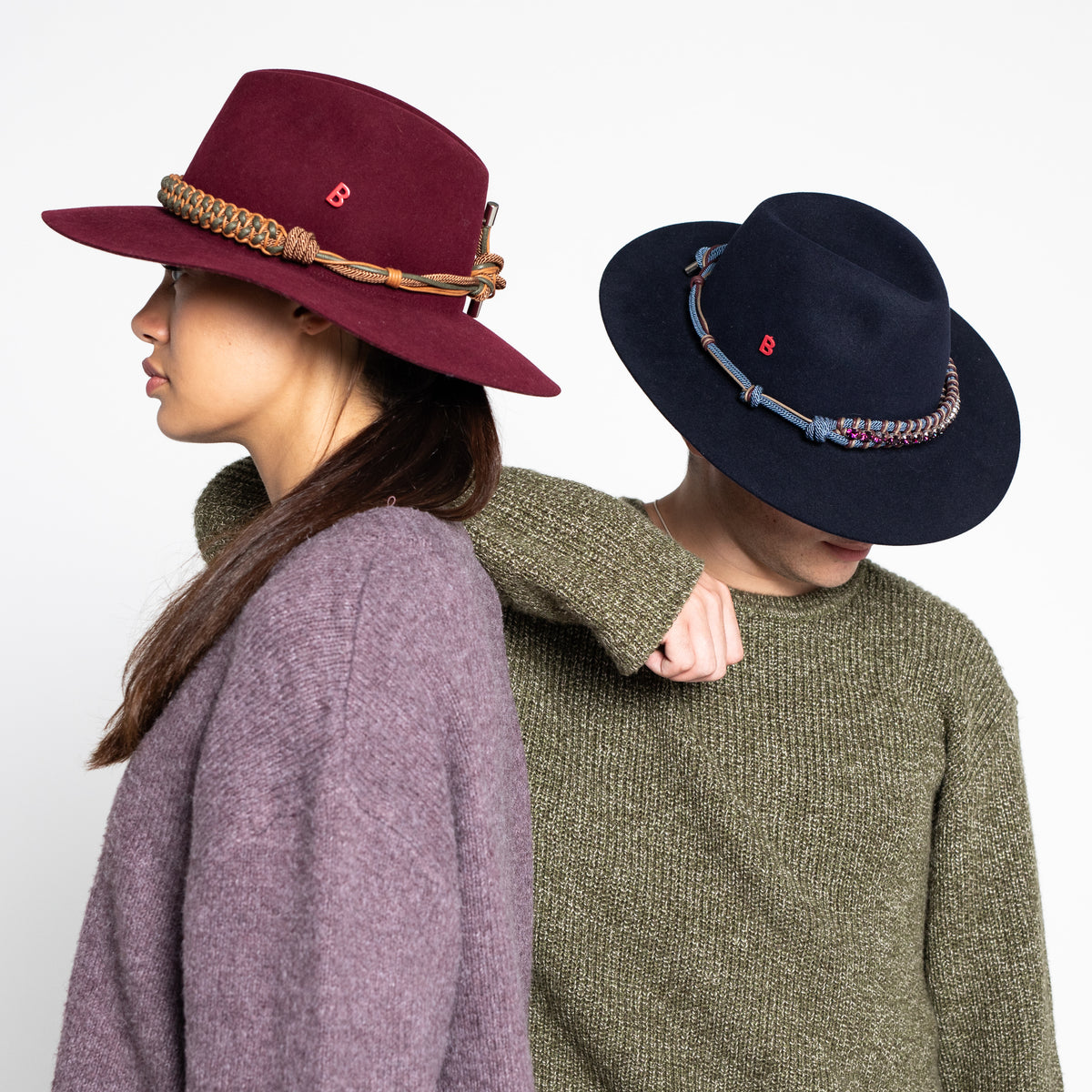 Two people wearing stylish hats with decorative bands including a patmos band with purple rhinestones on a white background