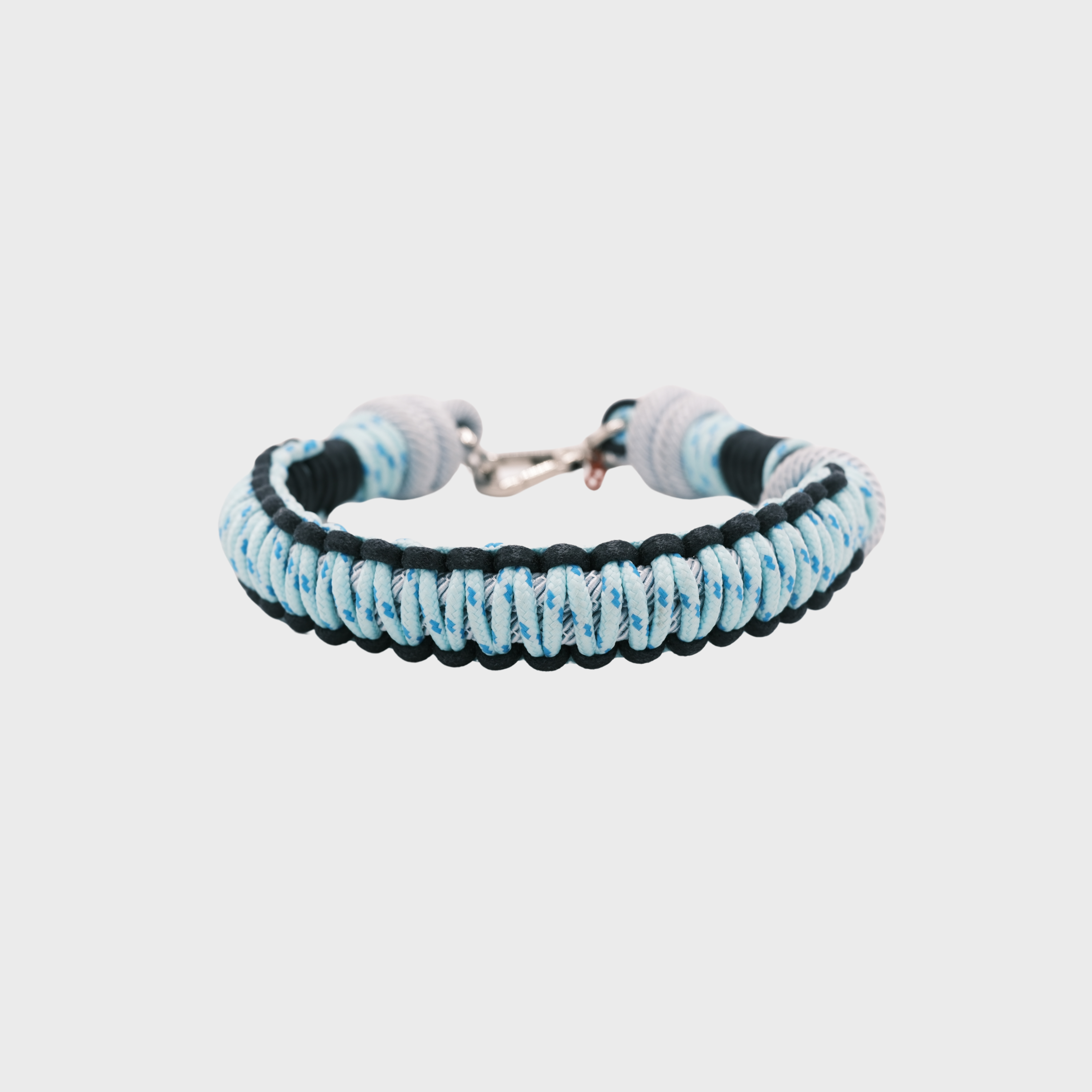 A braided macramé cord collar in shades of light blue and dark blue with a silver clasp, centered on a light gray background.