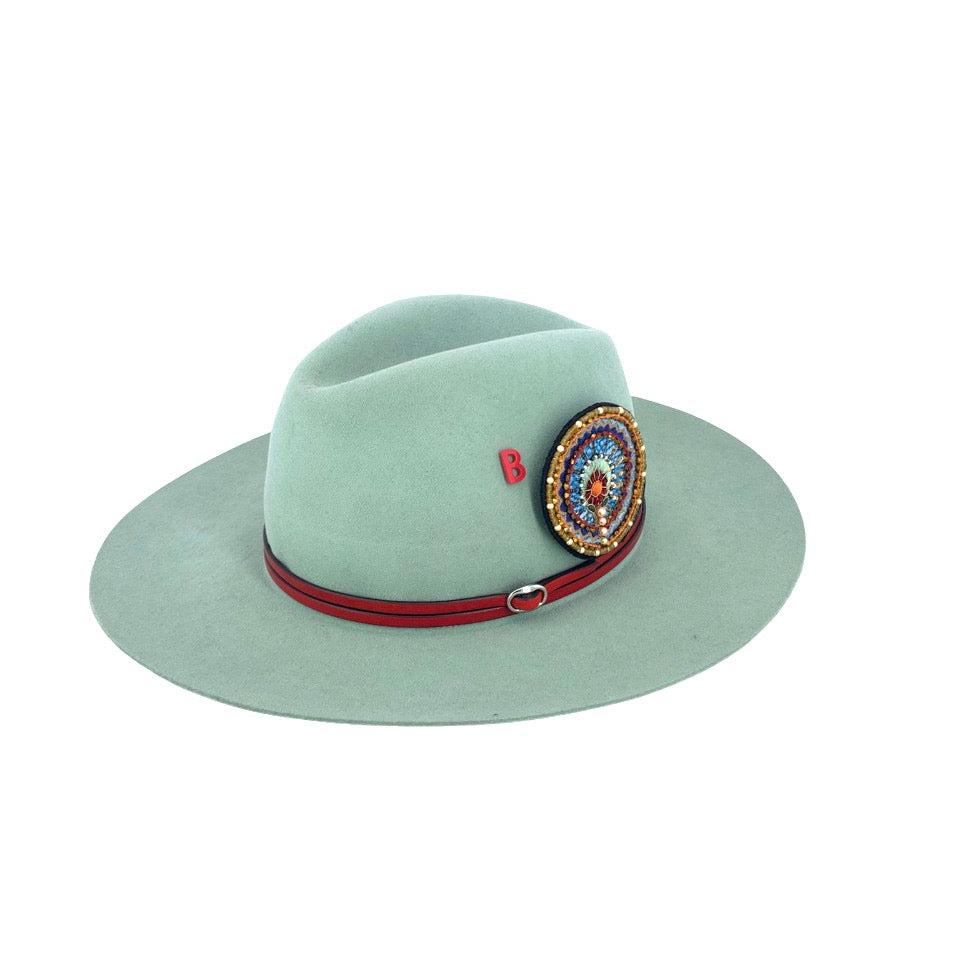 A wool hat with a red double leather band and an embroidered brooch. 