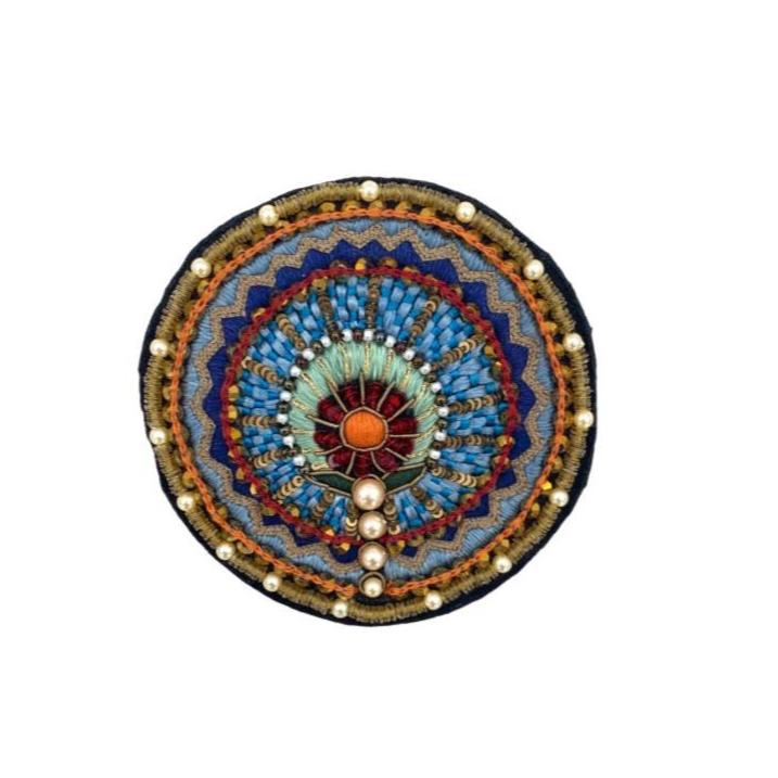 A circular brooch with multicolored floral embroidery and a pearl-like beaded edge.