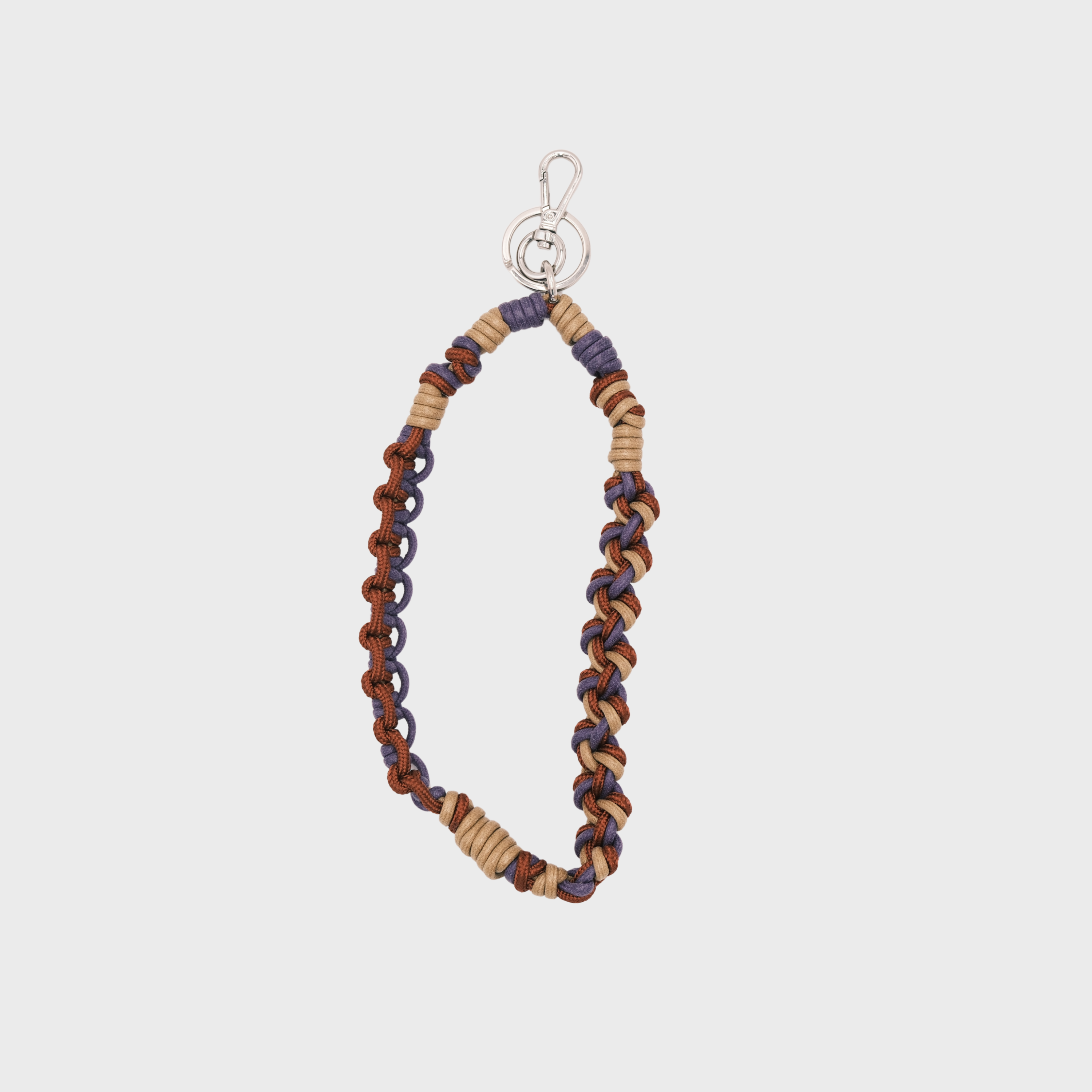 A bohemian-style woven macramé key chain with a silver-tone lobster clasp, featuring terracotta brown, beige and purple woven segments on a light gray background.