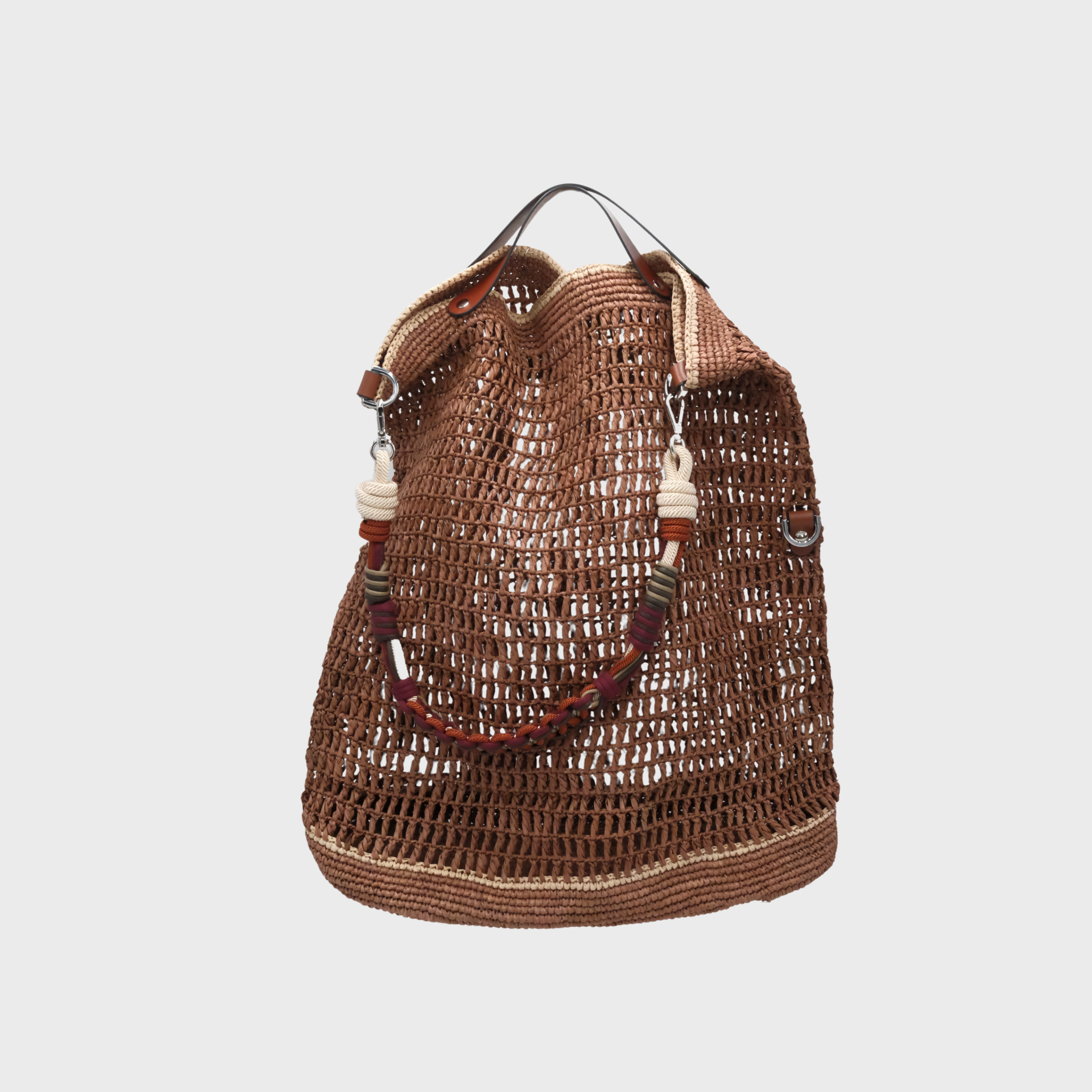 Brown with beige lines raffia bag with a square weaving with a burgundy, dark purple and orange beaded handle on a grey background