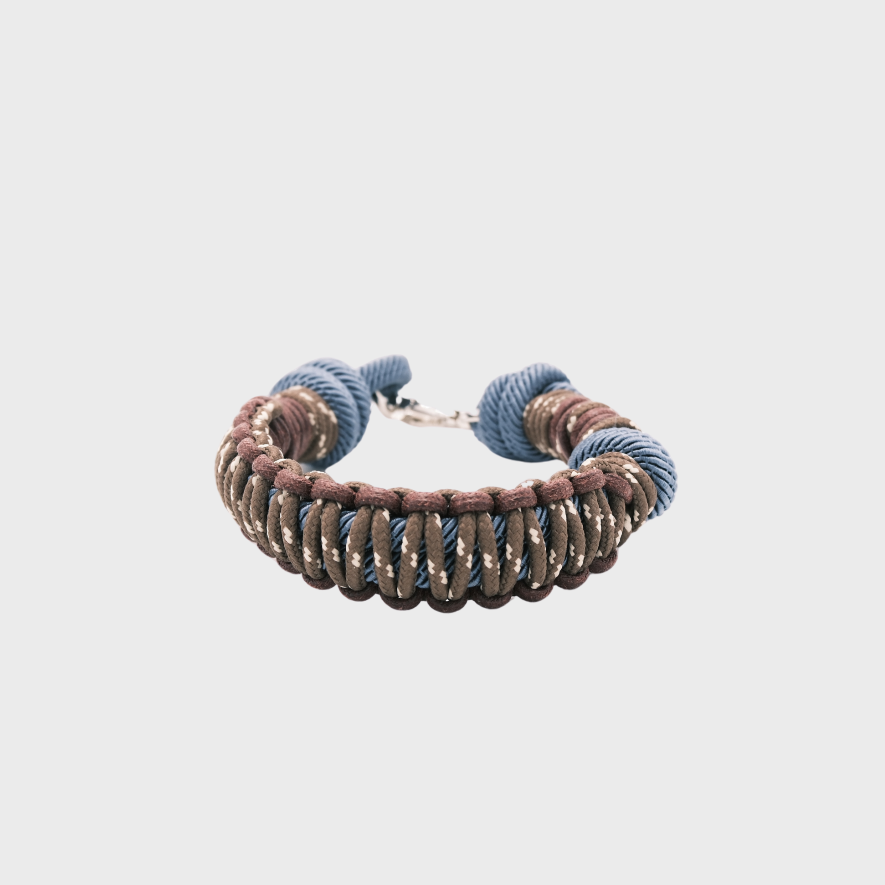 A braided macramé cord collar in shades of brown and blue with a silver clasp, centered on a light gray background.