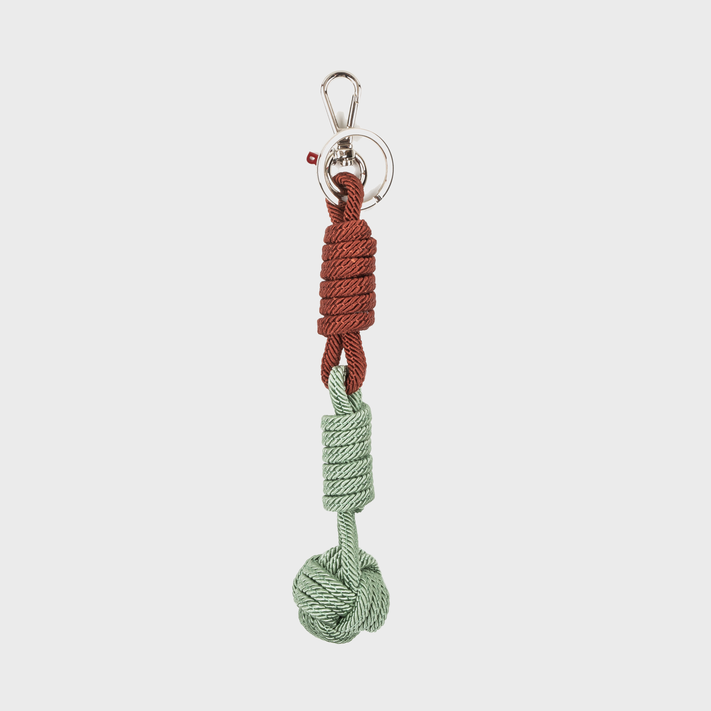 A macramé keychain representing a ball inspired by sailors knots. The straight upper part is brown and the ball part is water green. 