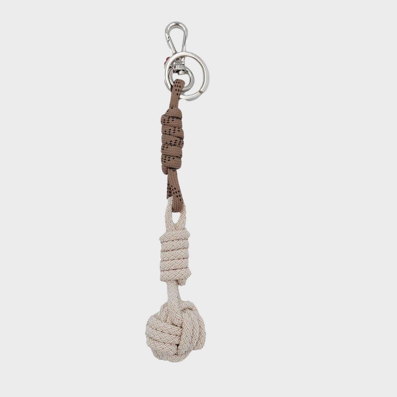 A macramé keychain representing a ball inspired by sailors knots. The straight upper part is brown and the ball part is grey. 