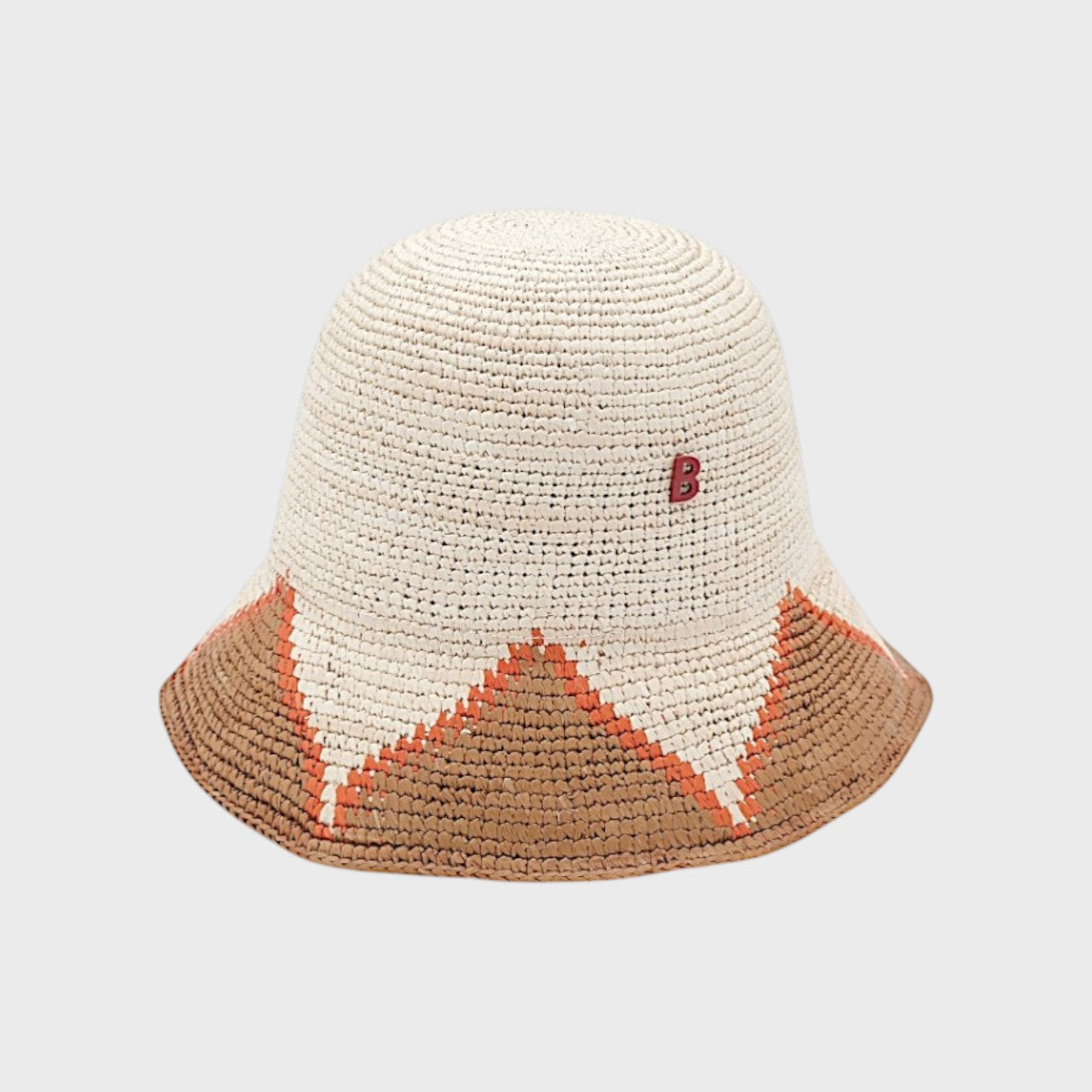 Two-toned raffia bucket hat with brown and orange and beige accents on a light gray background