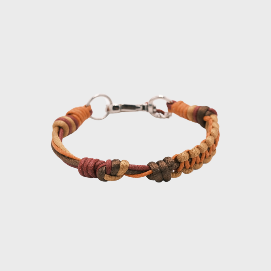 A thin braided bracelet with brown, orange and burgundy macramé, featuring a silver metal  clasp. 