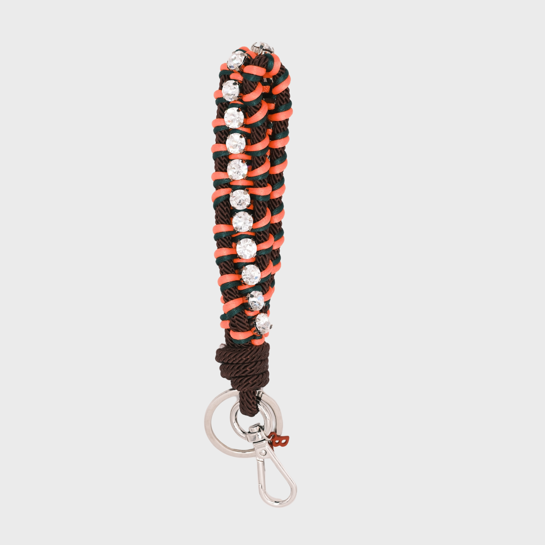 A macramé braided keychain strap featuring a brown and neon orange pattern, accented with a vertical row of silver rhinestones, and finished with a silver metal lobster clasp on a light gray background.