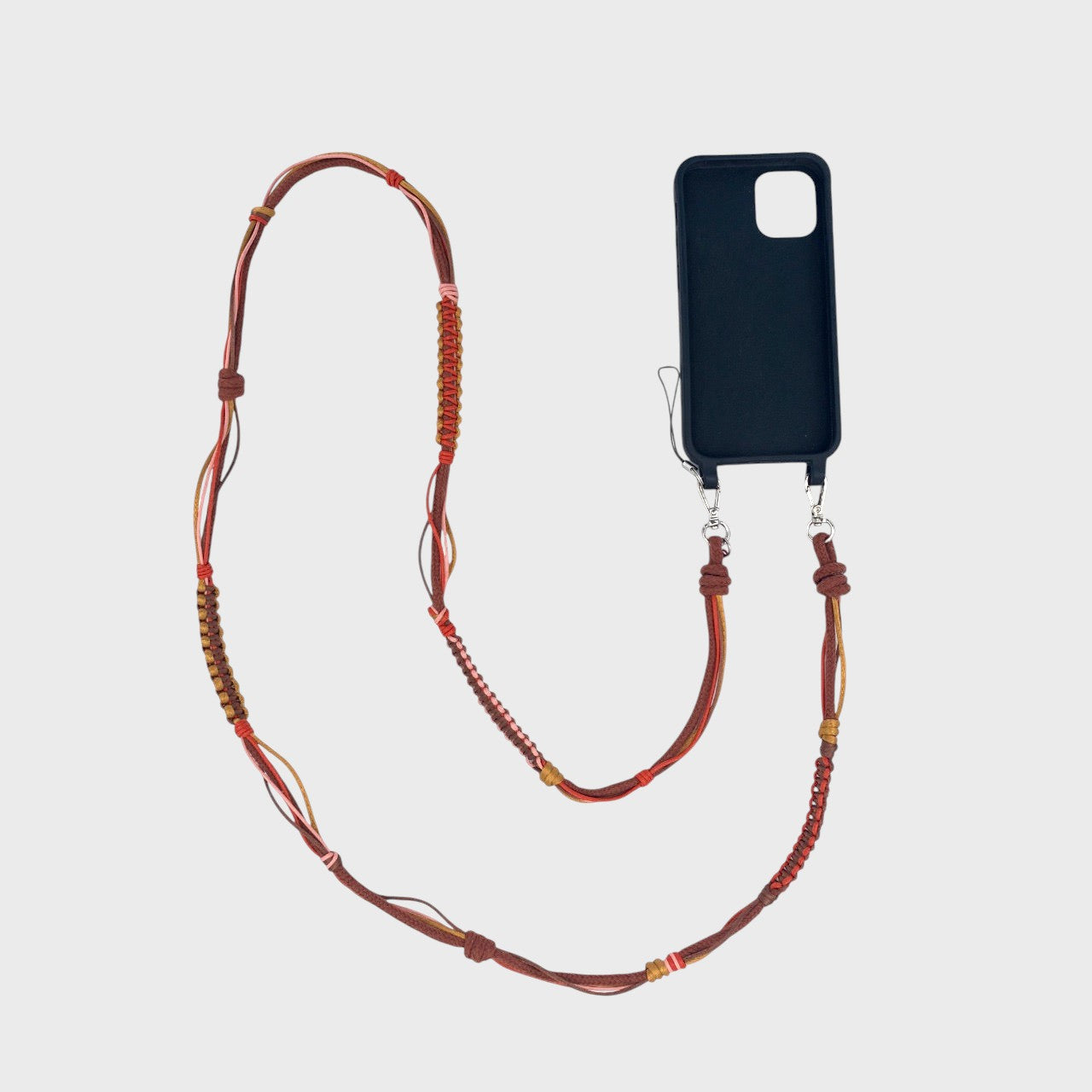 Brown, red, pink macramé woven phone lanyard with a black phone case on a white background. 