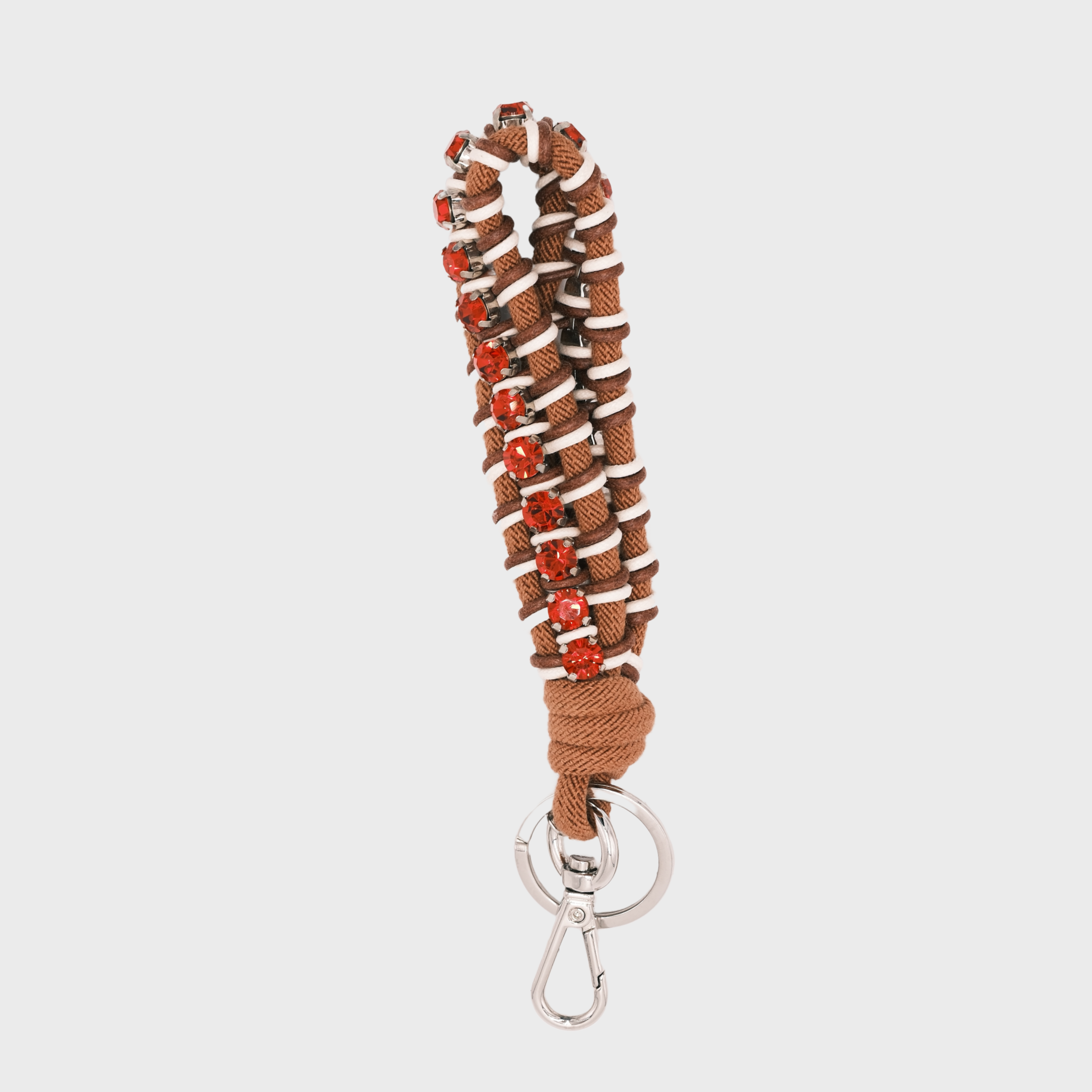 A macramé braided keychain strap featuring a brown and white pattern, accented with a vertical row of red rhinestones, and finished with a silver metal lobster clasp on a light gray background.