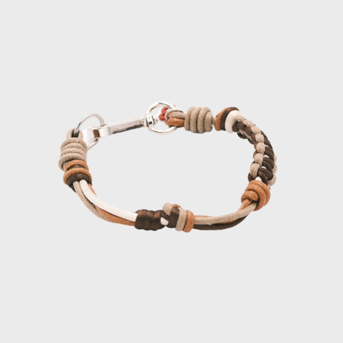 A thin braided bracelet with brown macramé, featuring a silver metal  clasp. 