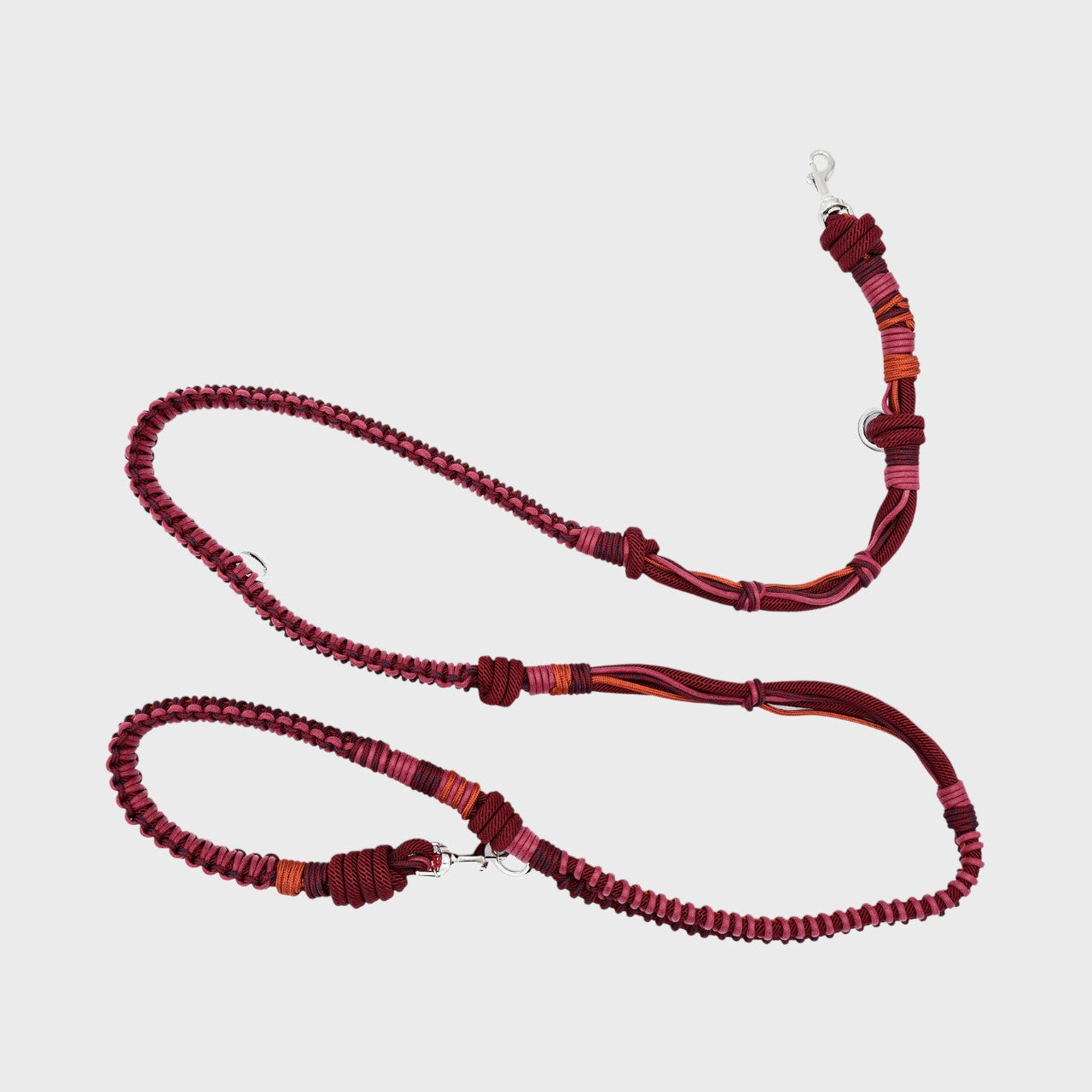 A braided macramé dog leash with burgundy and orange woven sections, and a silver metal hardware.