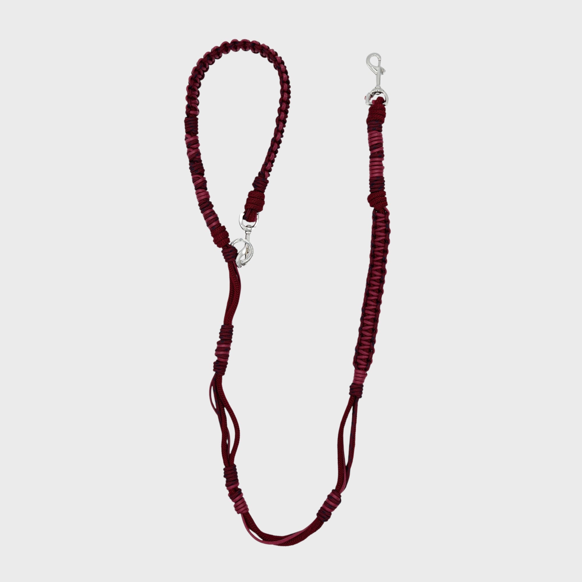 A braided macramé dog leash with brugundy light burgundy woven sections, and a silver metal hardware