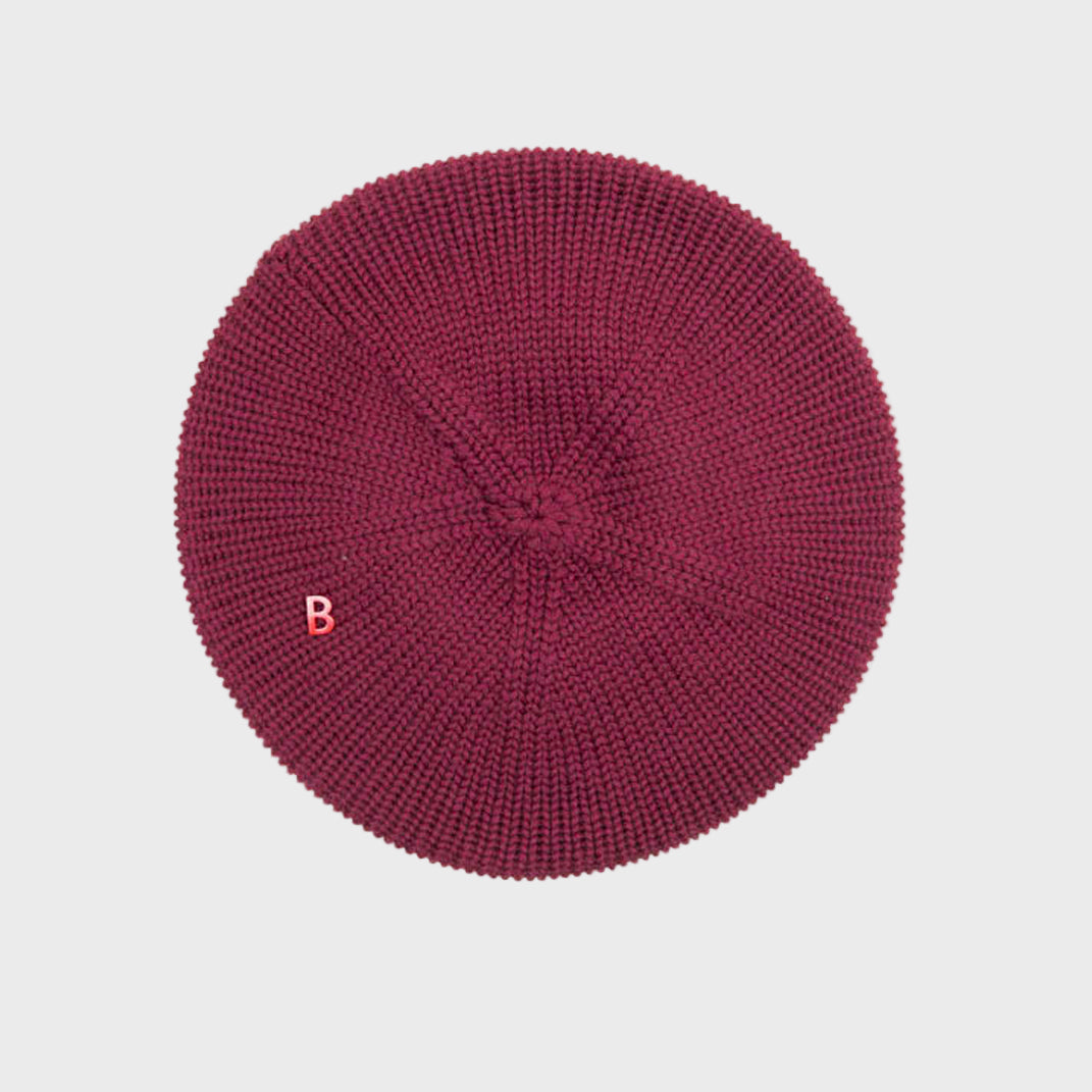Burgundy knit beret on a light gray background