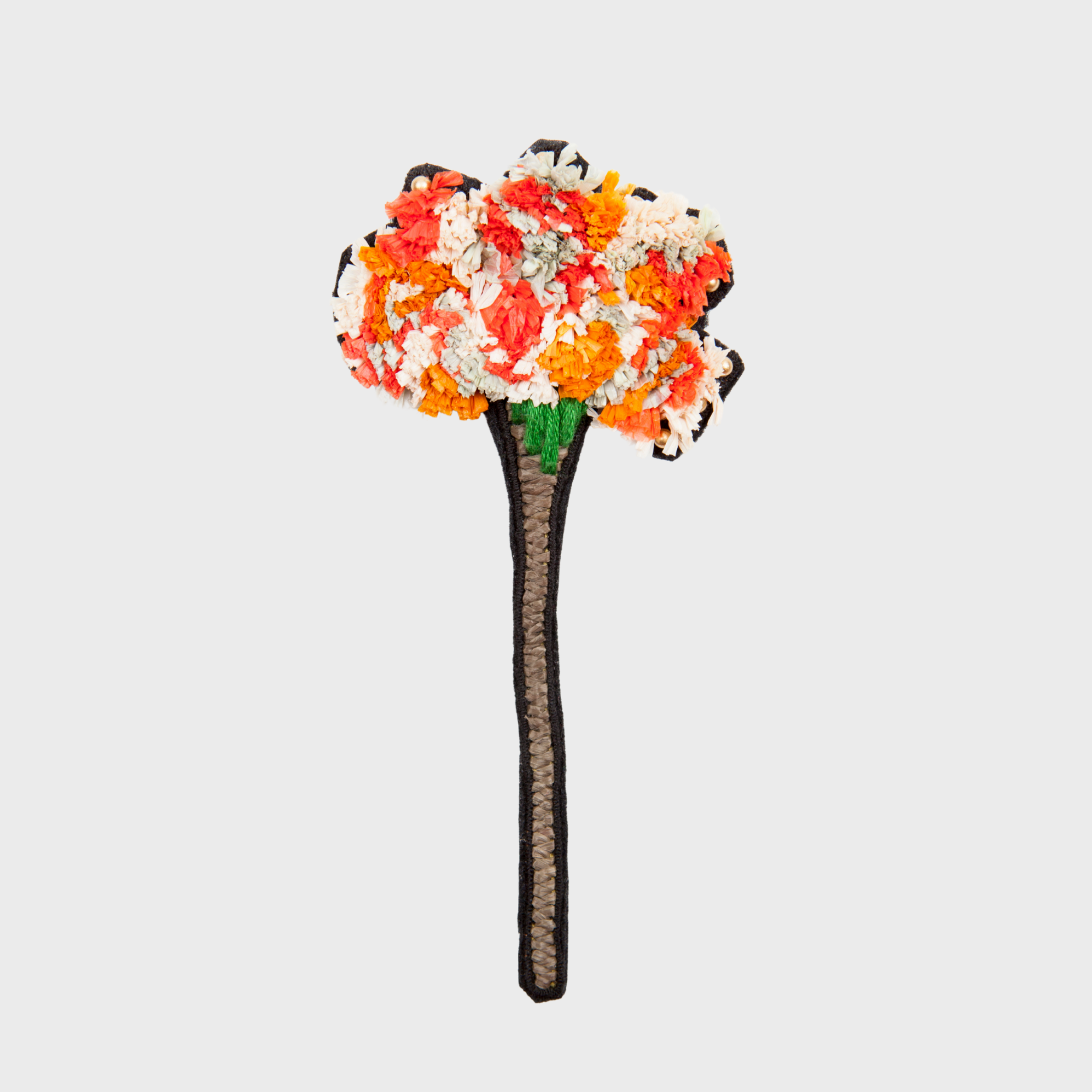 An embroidered Brooch representing a flower, with orange and white paper details and brown and green details. 
